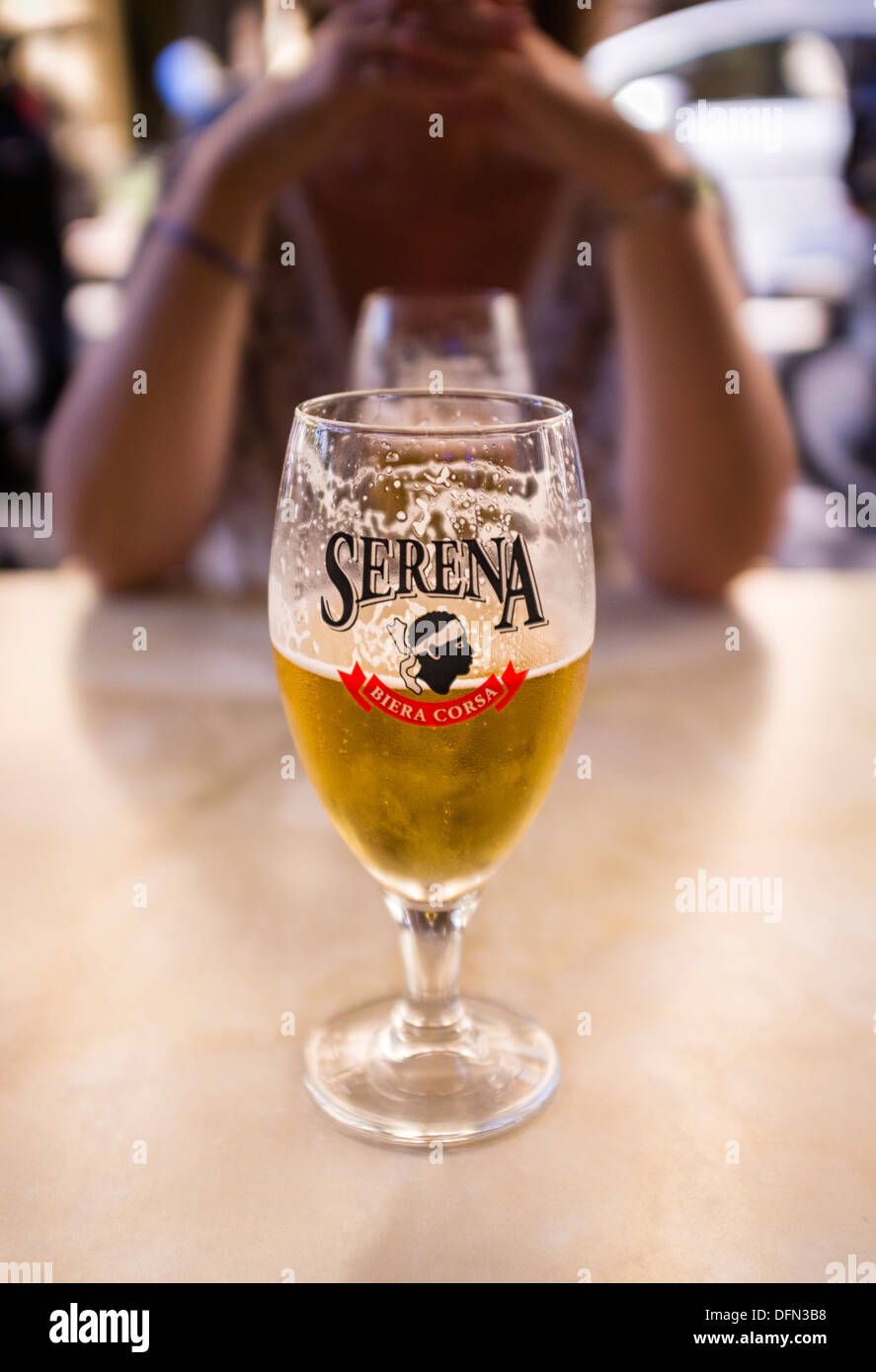Mezzo bicchiere pieno di birra su di una tavola di ristorante Foto Stock