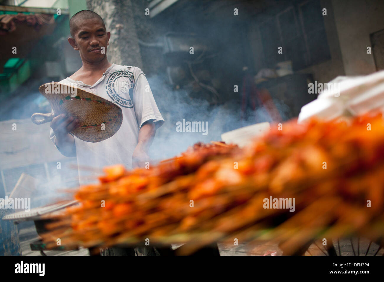 Un venditore ambulante cuochi spiedini di pollo su una griglia a carbone in Baclaran, Manila, Filippine. Foto Stock
