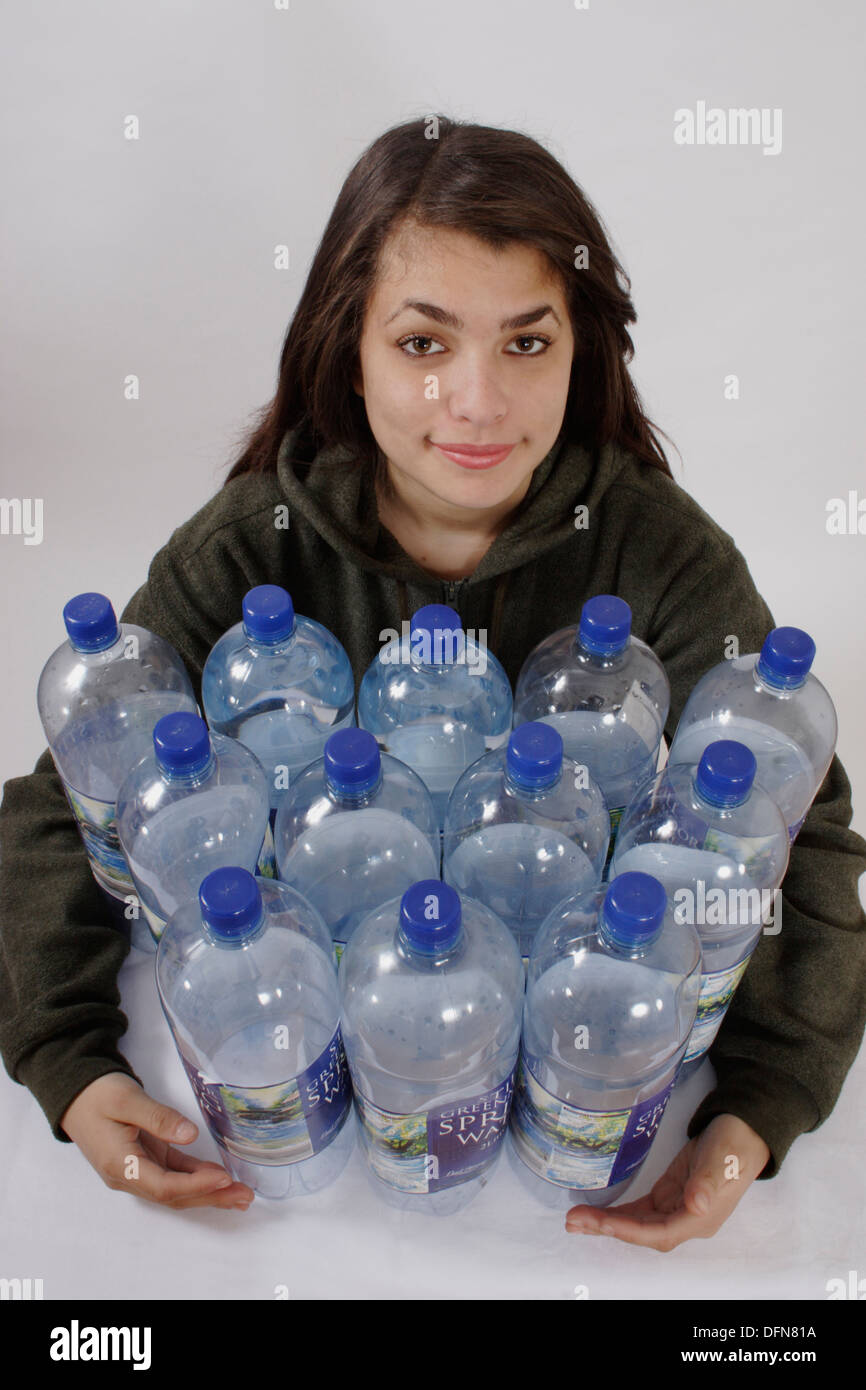 Ragazza adolescente in posa con 12 bottiglie di plastica per illustrare il riciclaggio di bottiglie in un vello di poliestere Foto Stock