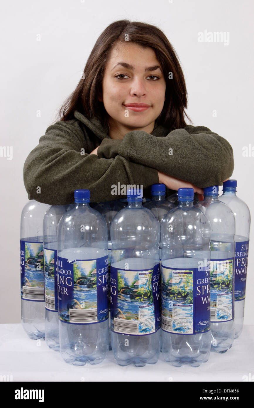 Ragazza adolescente in posa con 12 bottiglie di plastica per illustrare il riciclaggio di bottiglie in un vello di poliestere Foto Stock