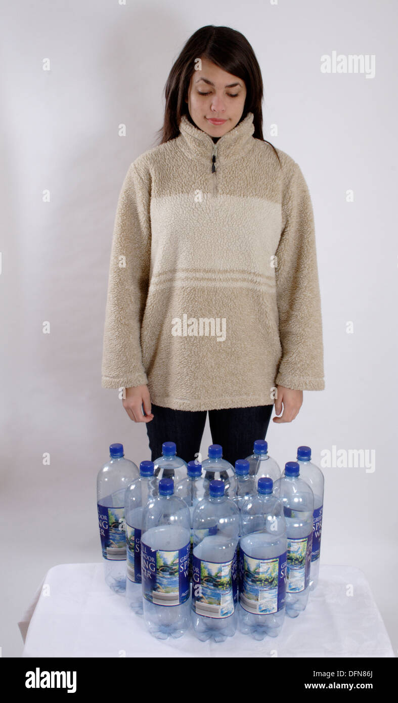 Ragazza adolescente in posa con 12 bottiglie di plastica per illustrare il riciclaggio di bottiglie in un vello di poliestere Foto Stock