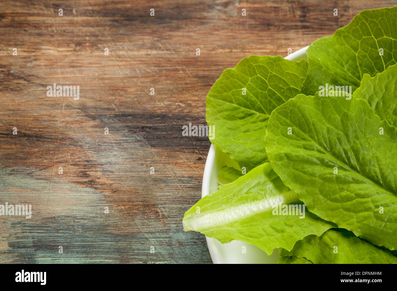 Fresco verde delle foglie di lattuga romana su una piastra contro un grunge di legno graffiato Foto Stock