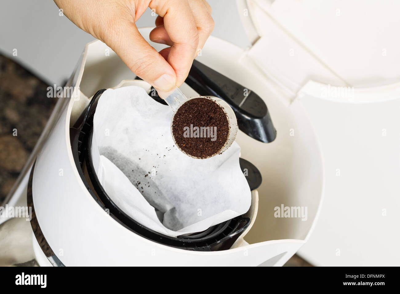 Angolo orizzontale foto di sesso femminile mettendo mano caffè fresco motivi in bianco sbiancato filtro per caffè con caffè e pietra Foto Stock