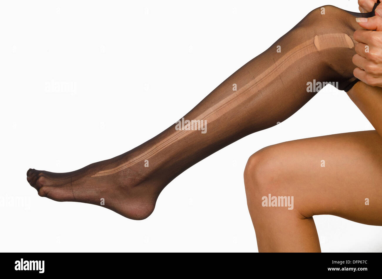Prendere di un collant strappati sulle gambe femmina Foto Stock