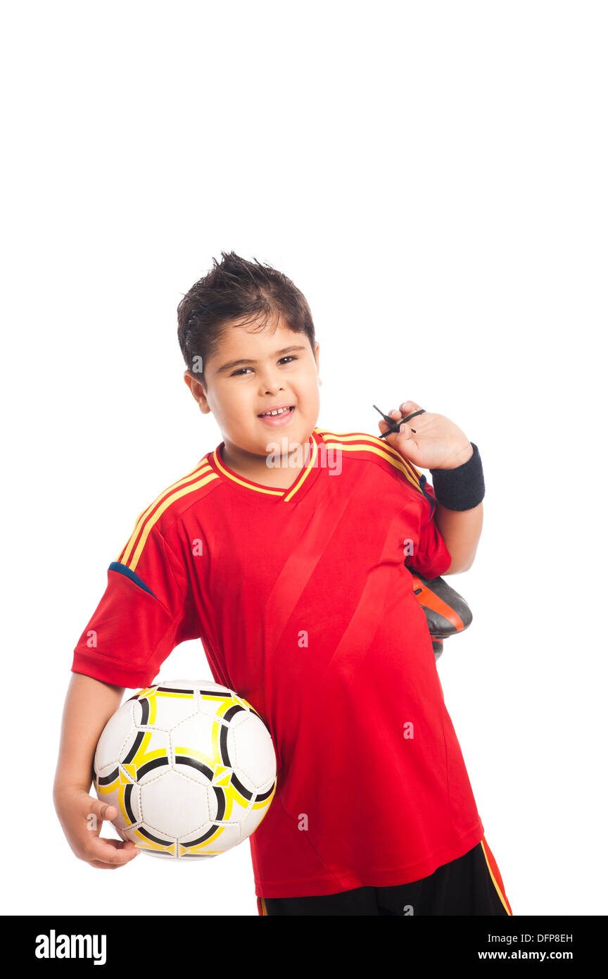 Ragazzo che porta un pallone da calcio e le sue scarpe Foto Stock