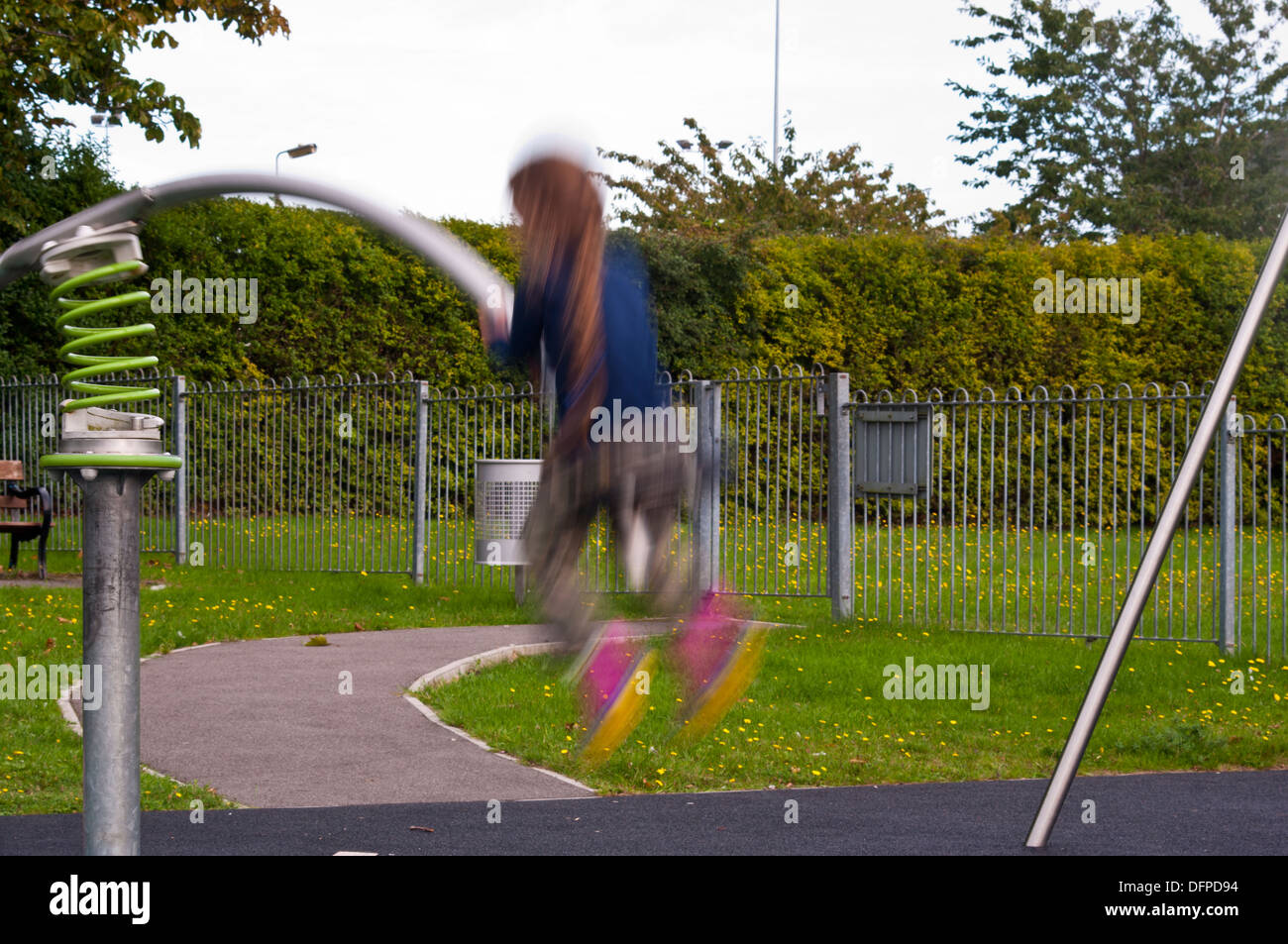 Bambina rimbalza su un altalena in un parco giochi per bambini con soggetti in movimento le sfocature Foto Stock