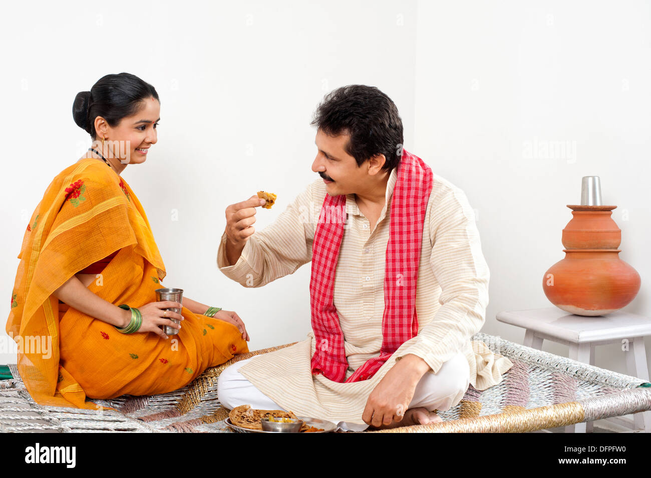 Uomo a mangiare cibo con sua moglie seduta vicino a lui Foto Stock