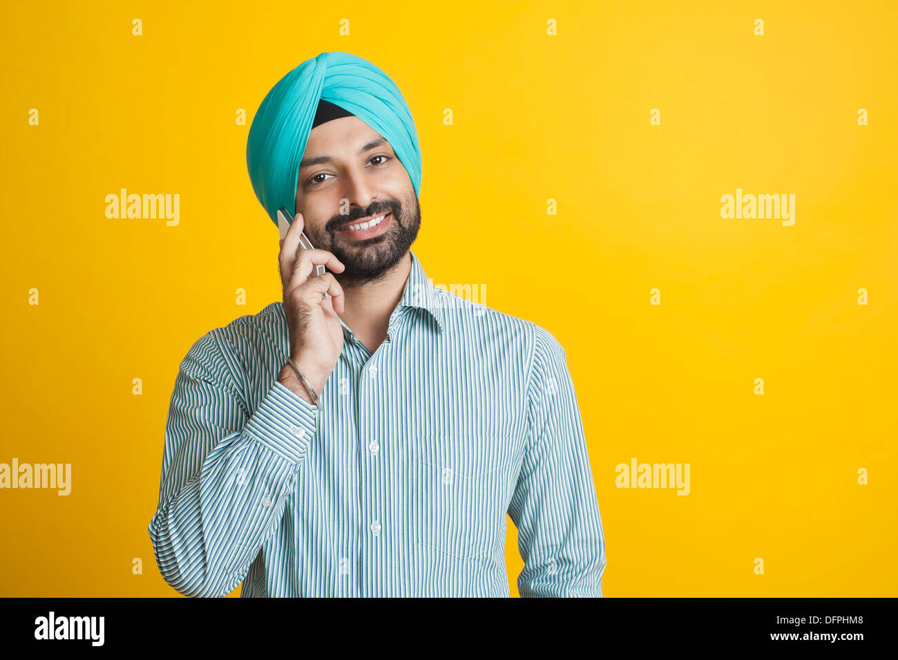 La religione Sikh l uomo a parlare su un telefono mobile e sorridente Foto Stock