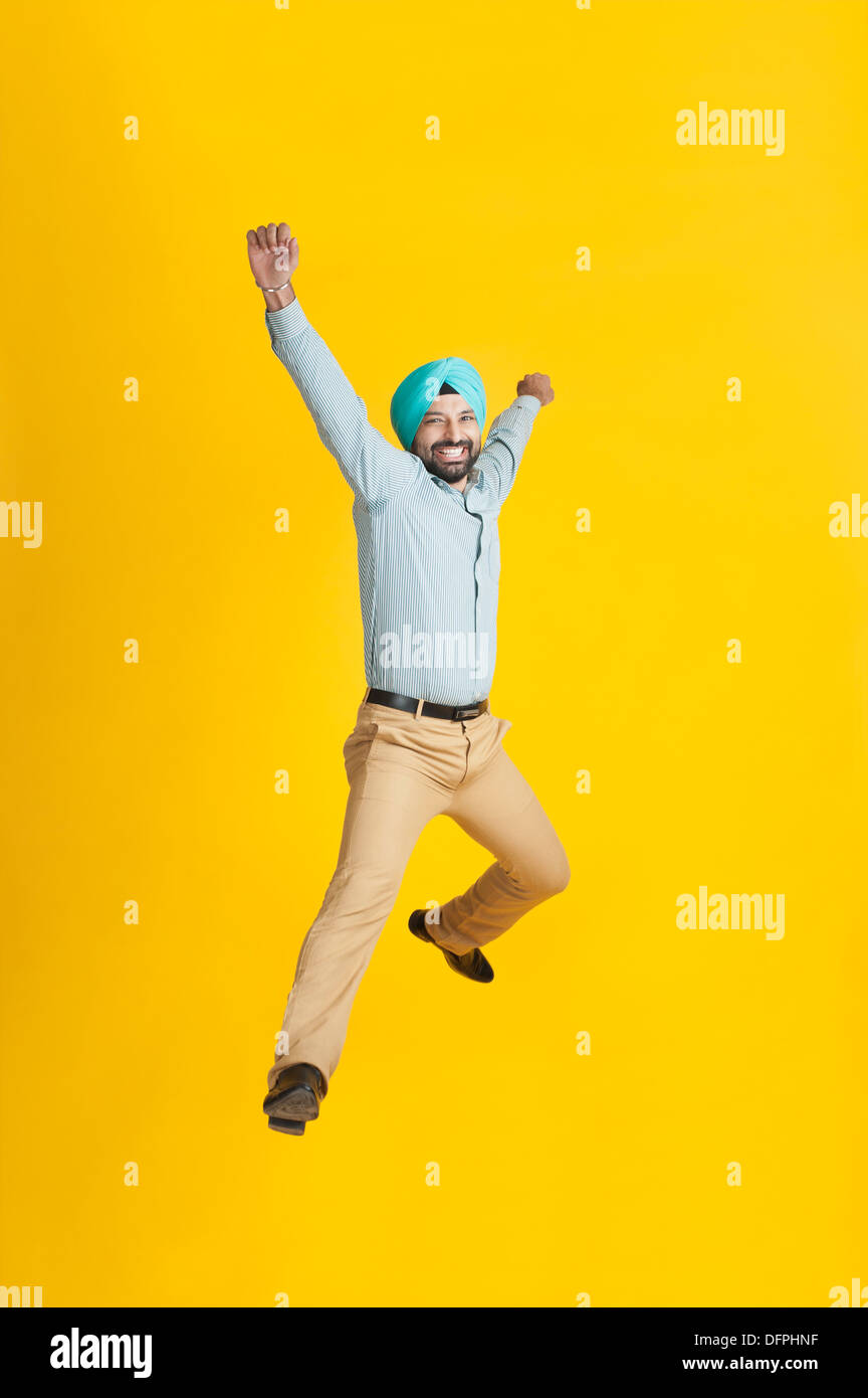 Eccitato uomo Sikh jumping e sorridente Foto Stock