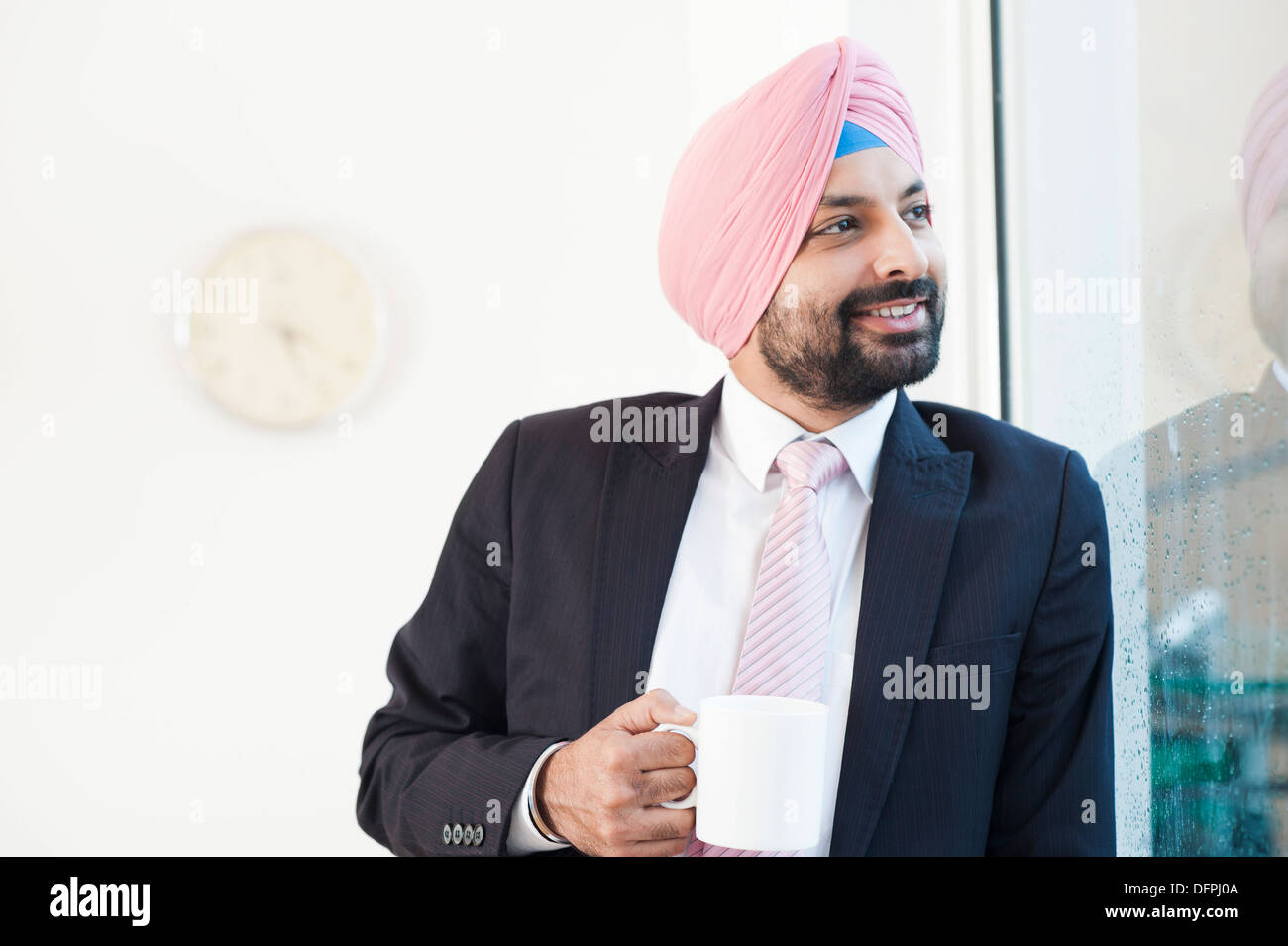 Imprenditore guardando fuori della finestra mentre si beve il caffè Foto Stock