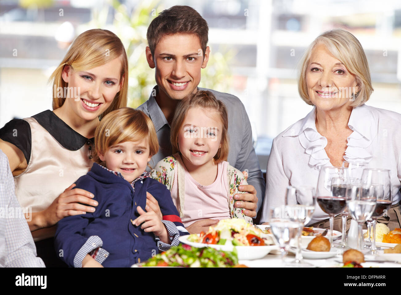 La famiglia felice con bambini e la nonna seduta al tavolo pranzo Foto Stock