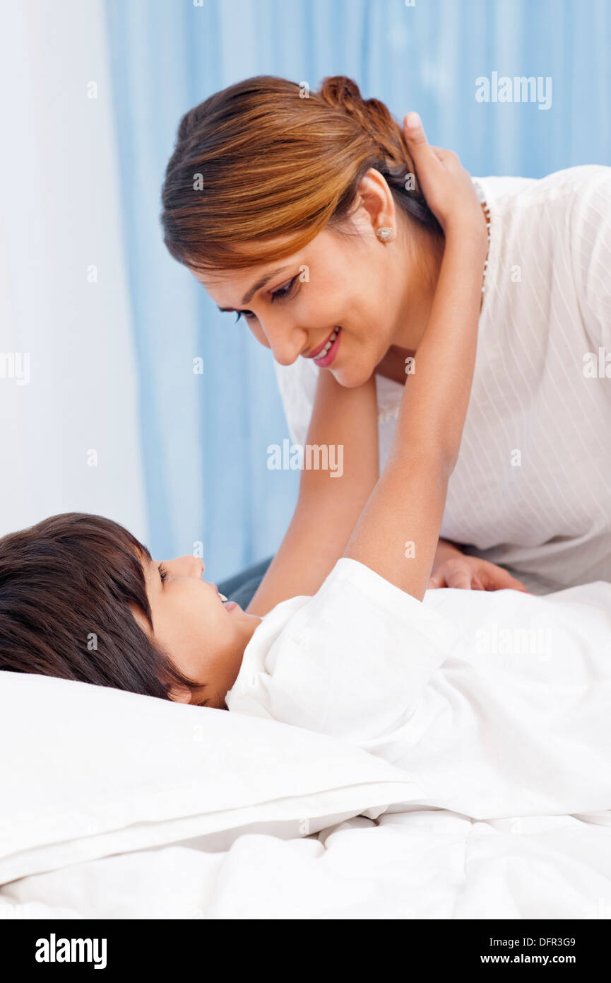 Ragazzo abbraccia il suo madre sul letto Foto Stock