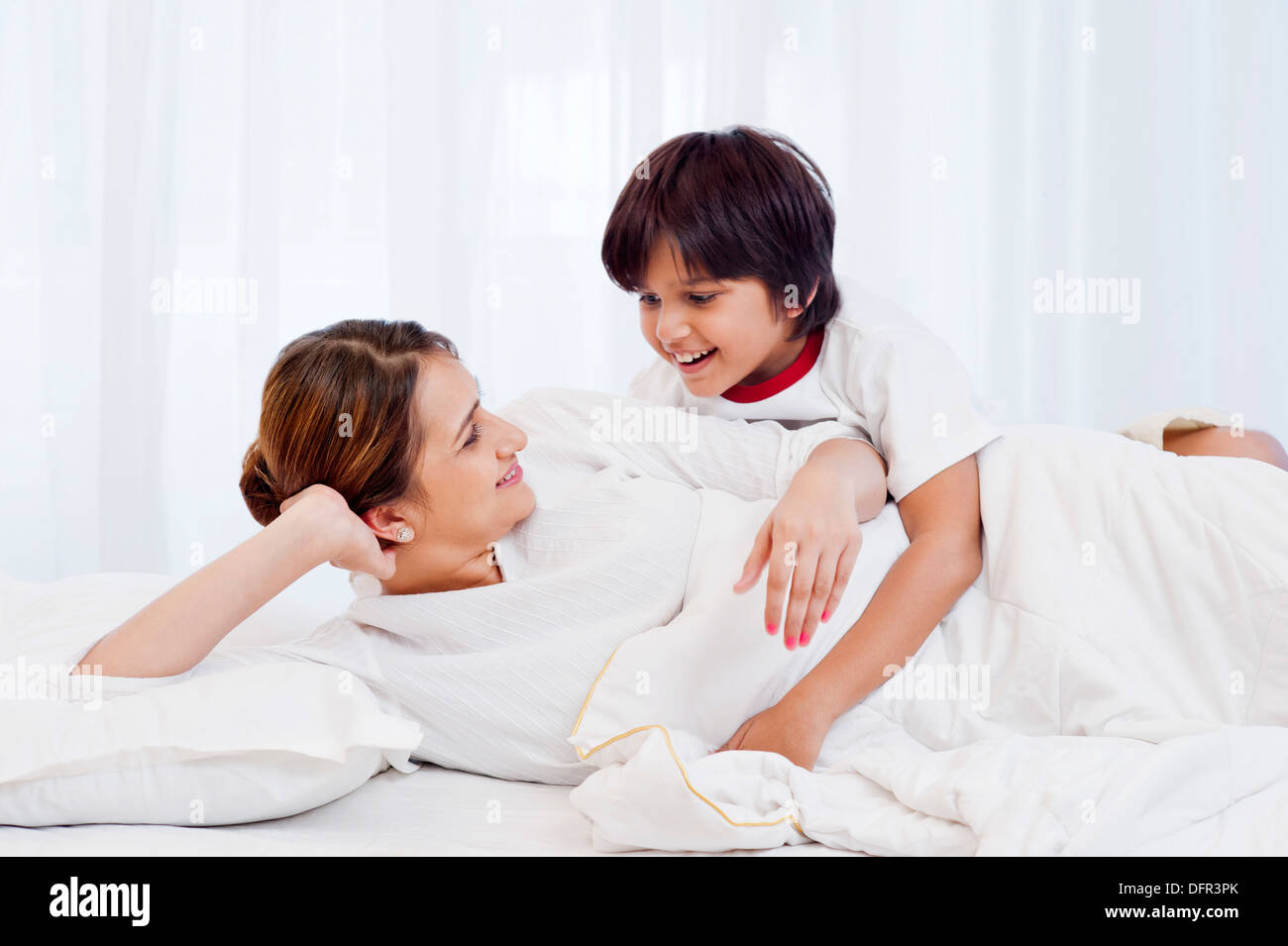 Donna e suo figlio giacente sul letto e sorridente Foto Stock