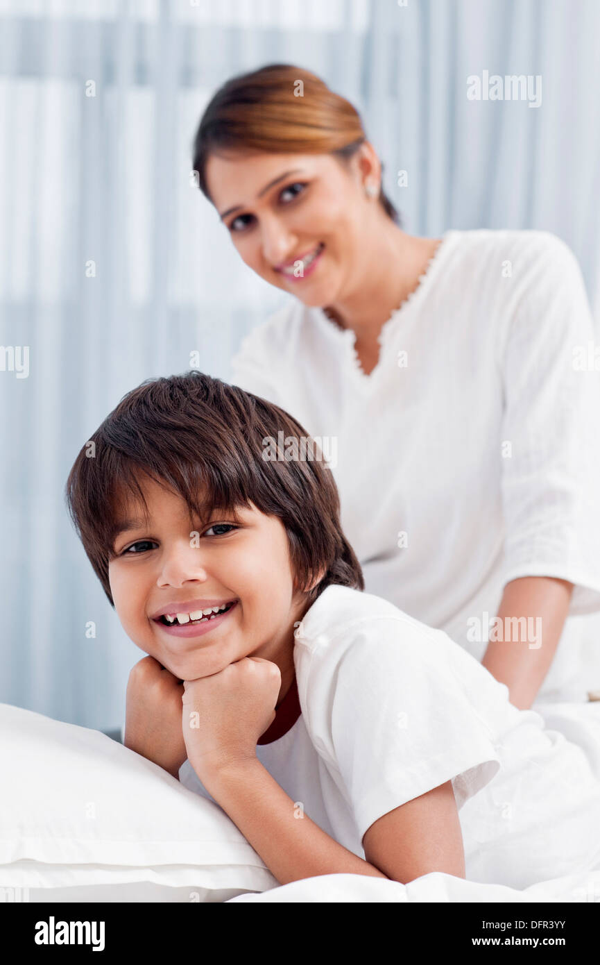 Ritratto di un ragazzo disteso sul letto con sua madre in background Foto Stock