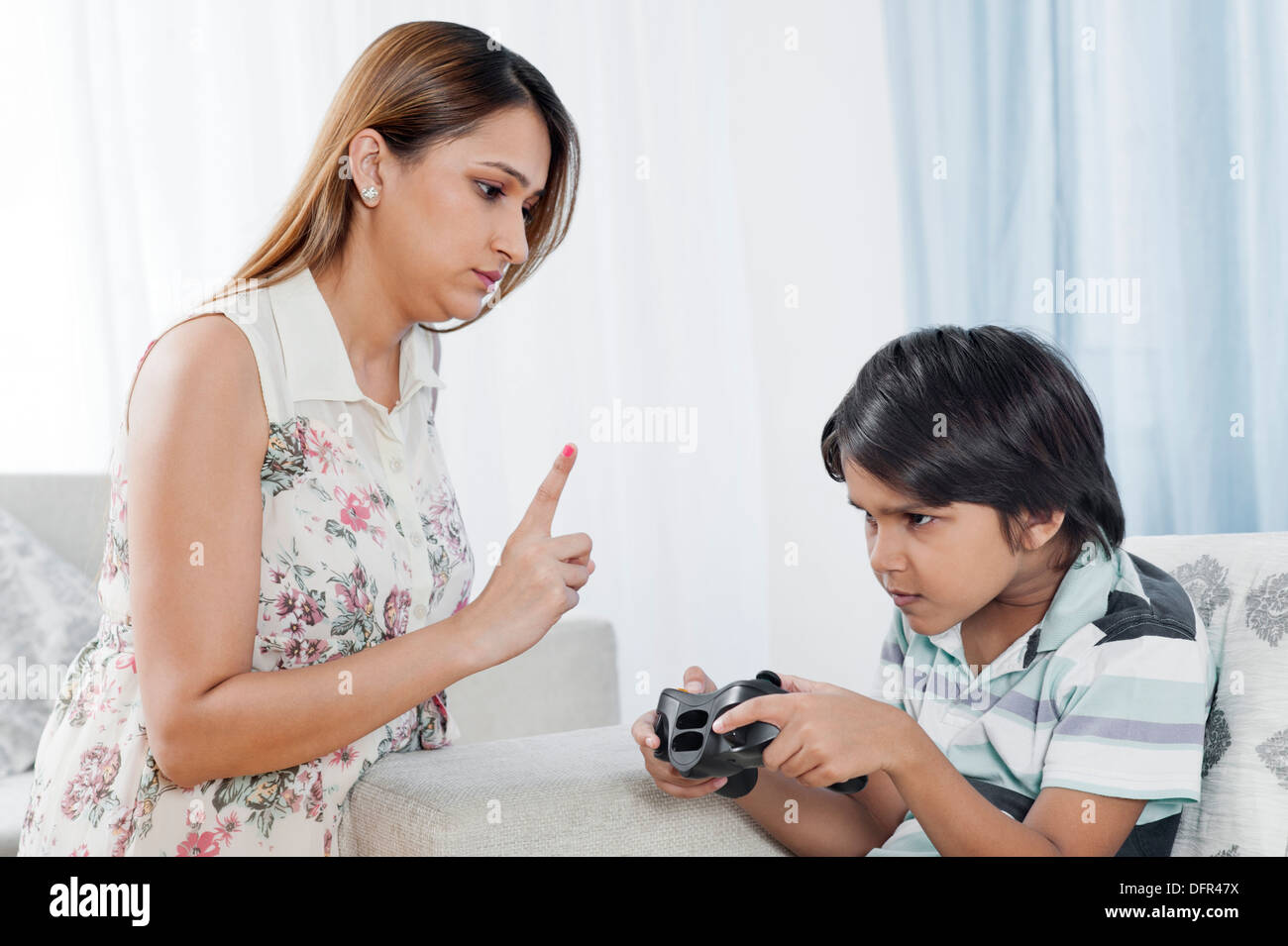 Donna scolding suo figlio la riproduzione di video gioco Foto Stock