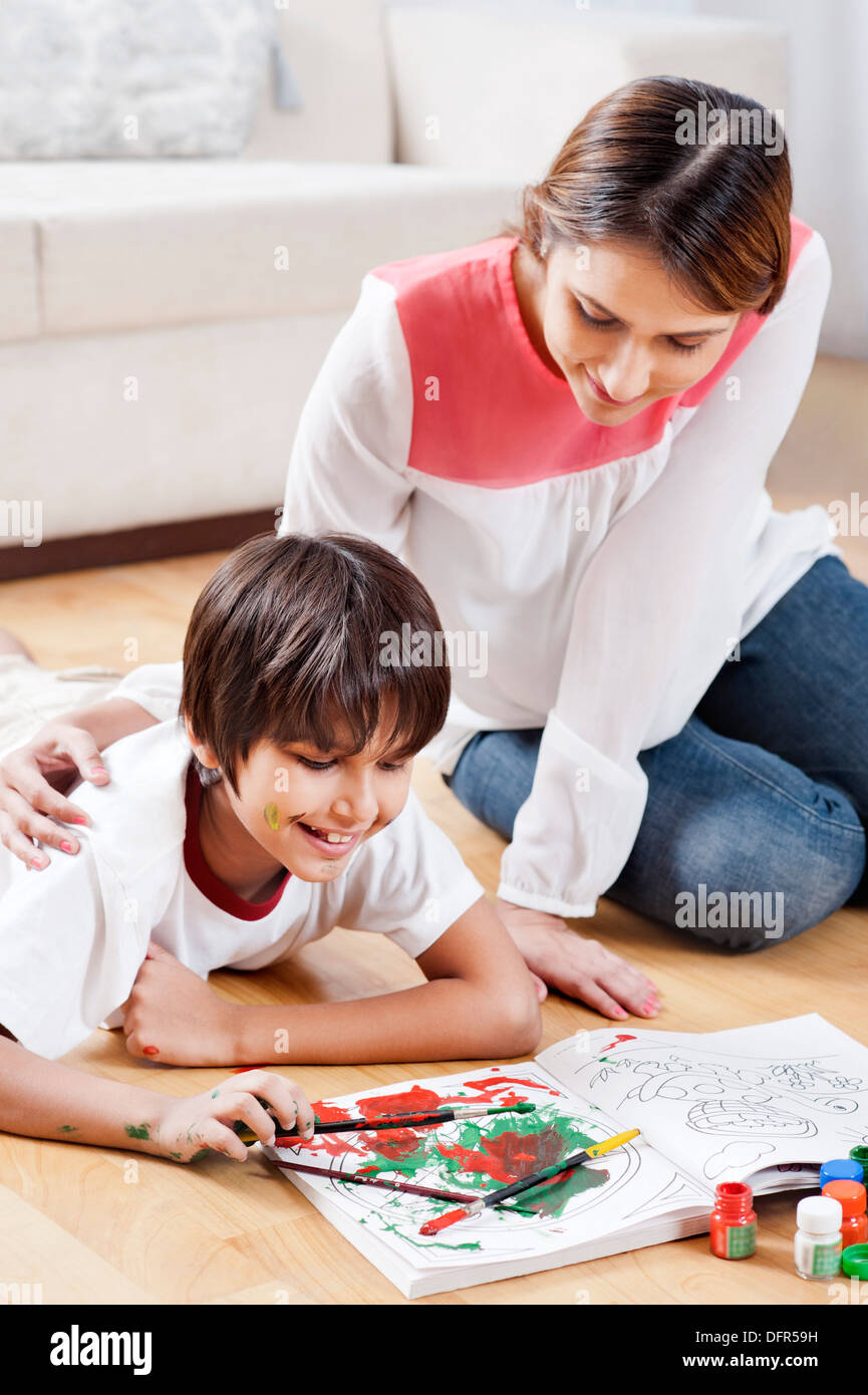 Ragazzo facendo la colorazione con sua madre seduta accanto a lui Foto Stock