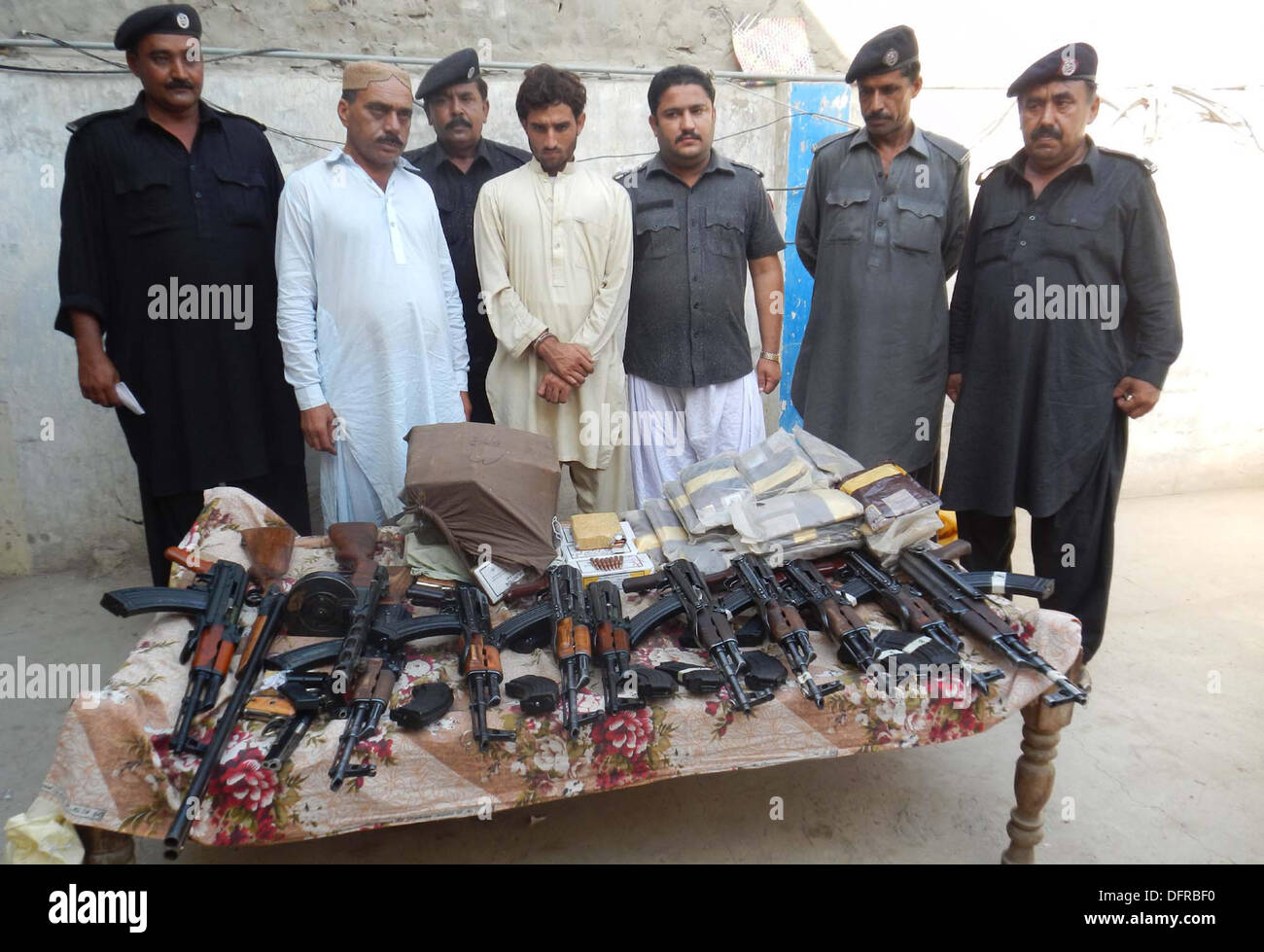 Accise i funzionari di polizia sono mostra sequestrati armi e droghe che recuperato durante il raid su un carrello in movimento a Karachi dal a Peshawar, a Ubauro Martedì, Ottobre 08, 2013. La polizia di accise recuperato un numero di pistole di macchina, vicino a circa cinque giri migliaia e quaranta chili di Charas Foto Stock