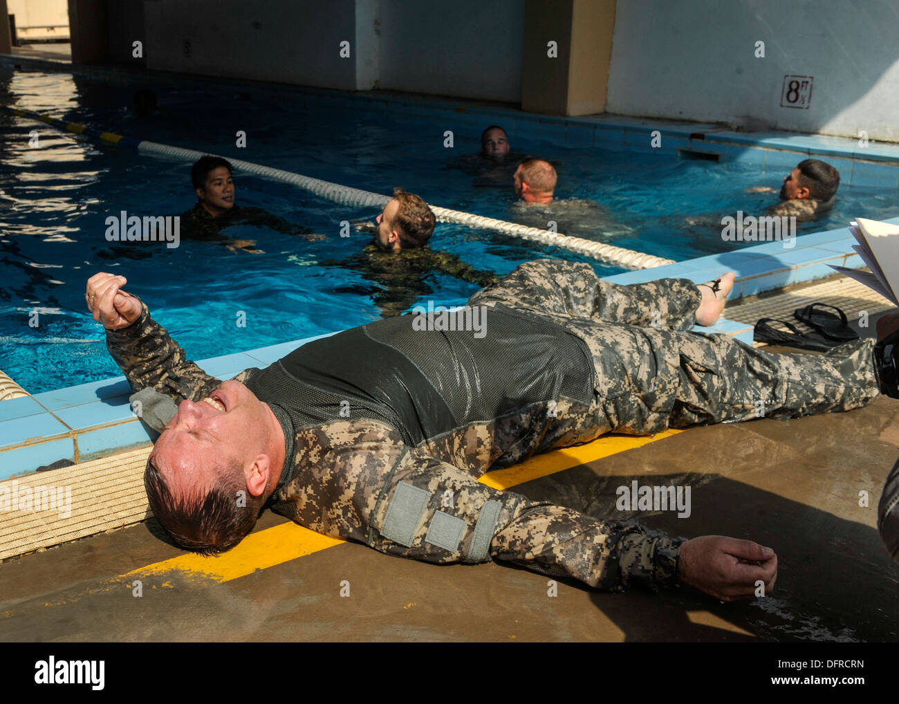 Esercito Lt. Col. John Warner giace a terra dopo il completamento di un relè nuotare gara. I concorrenti nuotarono per un giro della piscina mentre wea Foto Stock