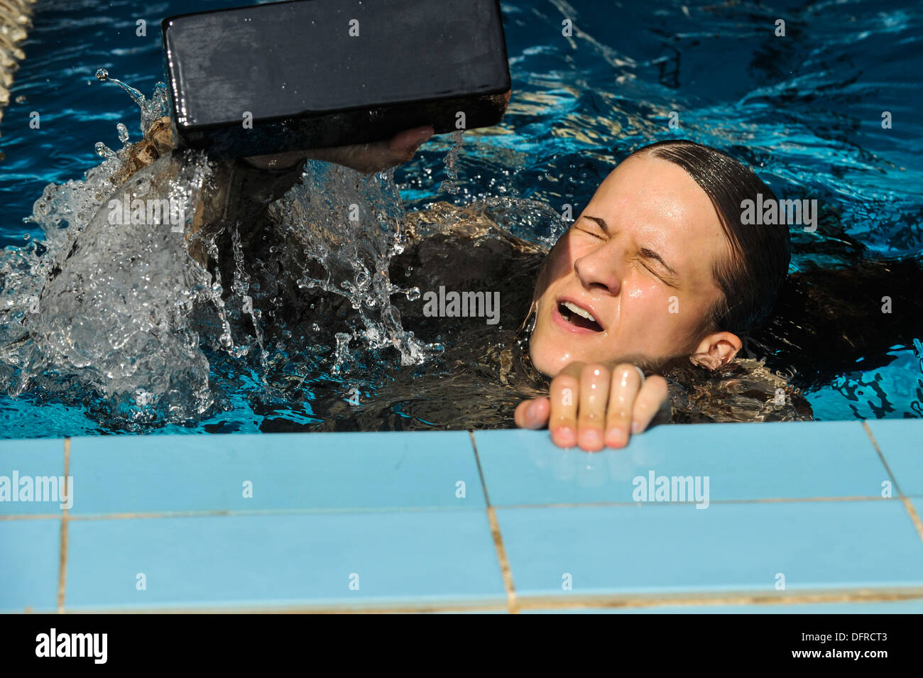 Marine Corps Sgt. Jennifer Slown solleva un mattone al di fuori dell'acqua durante un relè nuotare gara. I concorrenti nuotarono per un giro della piscina Foto Stock
