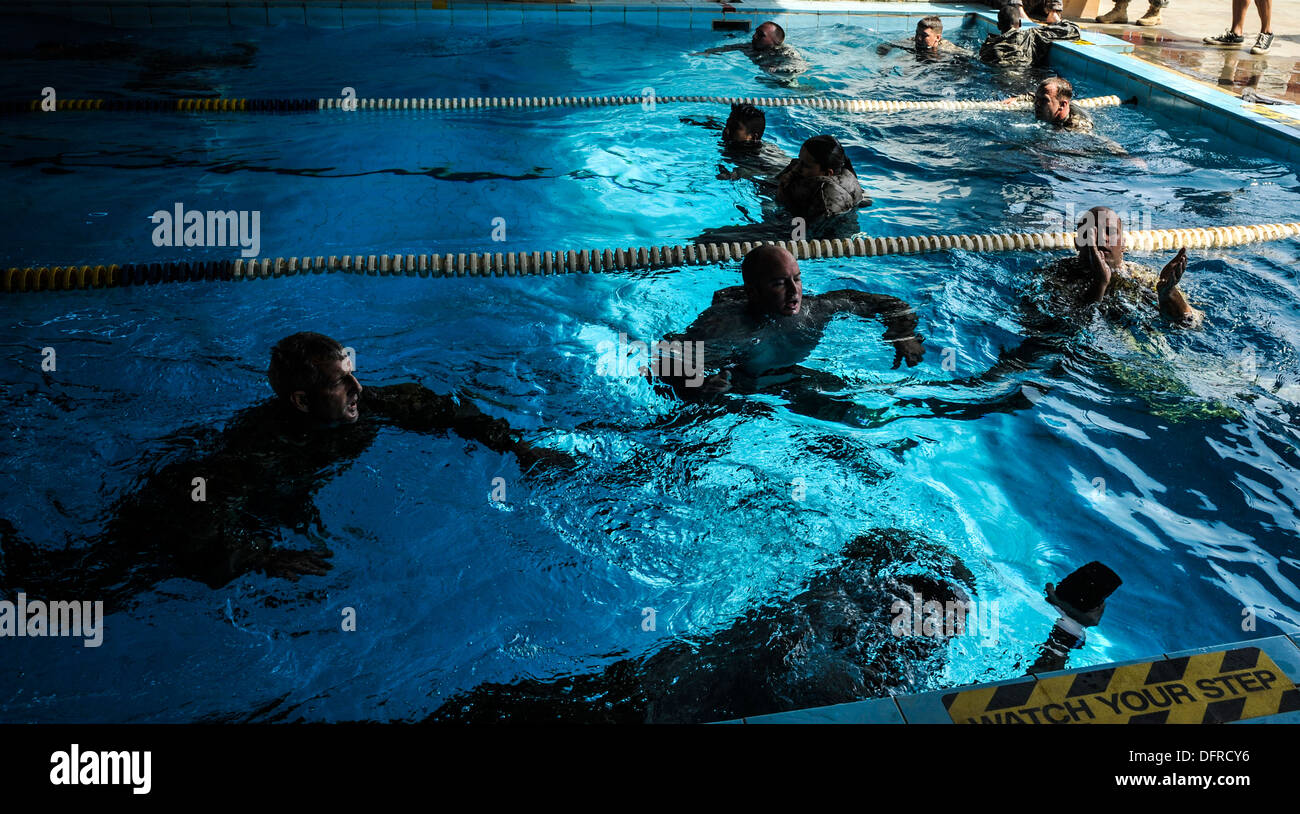 Nuotatori battistrada acqua durante un relè nuotare gara. I concorrenti nuotarono per un giro della piscina indossando il loro combattimento uniforme e carr Foto Stock