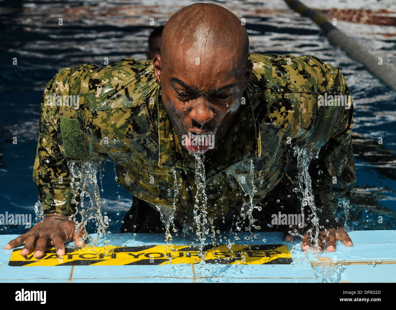 Navy Hospital Corpsman 2a classe Rolando Brooks spinge se stesso al di fuori della piscina durante un relè nuotare gara. Nuotarono concorrenti uno l Foto Stock