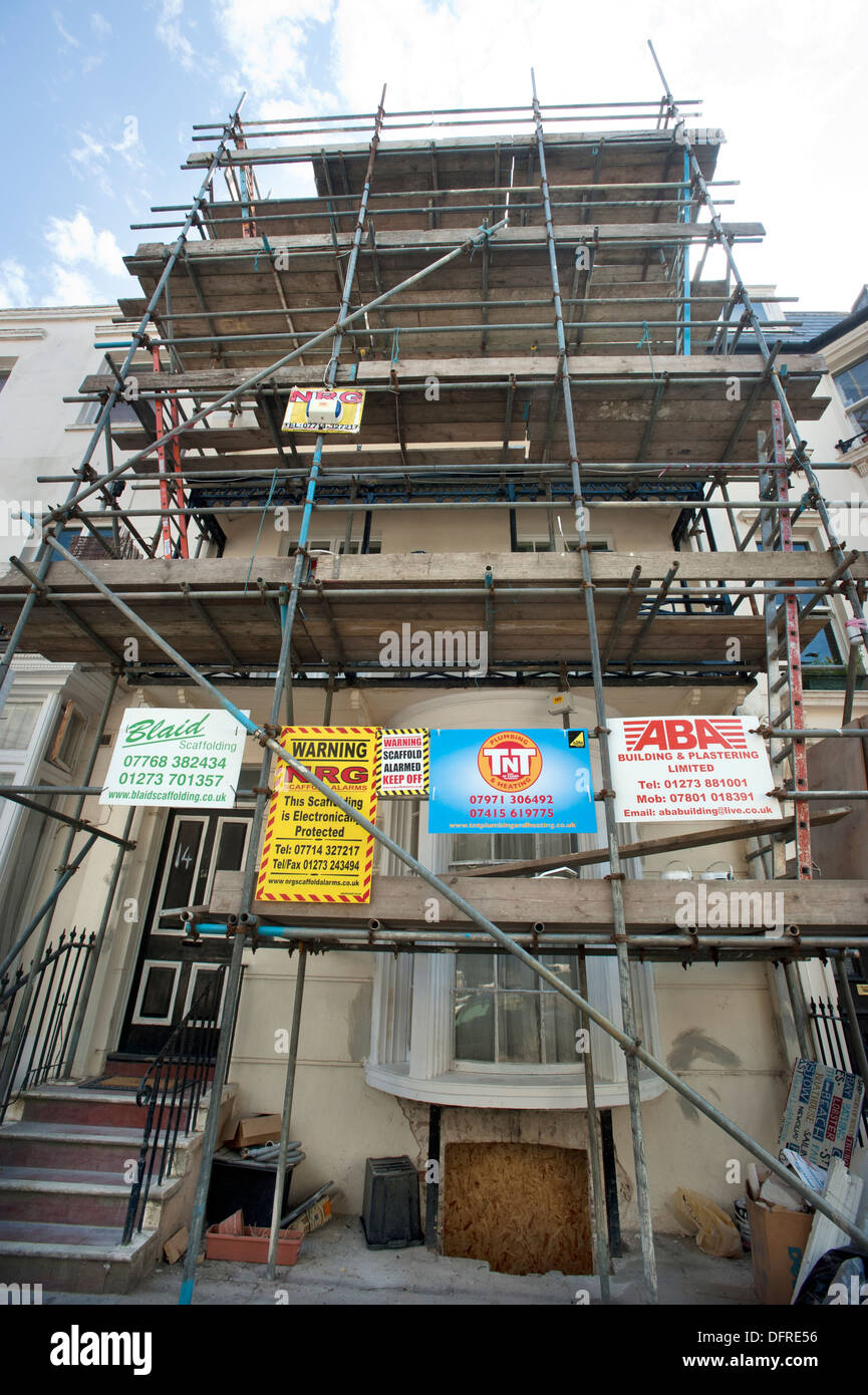 Costruttori' pannelli pubblicitari sui ponteggi su un 1822 costruito Regency House in restauro nel centro di Brighton. Foto Stock