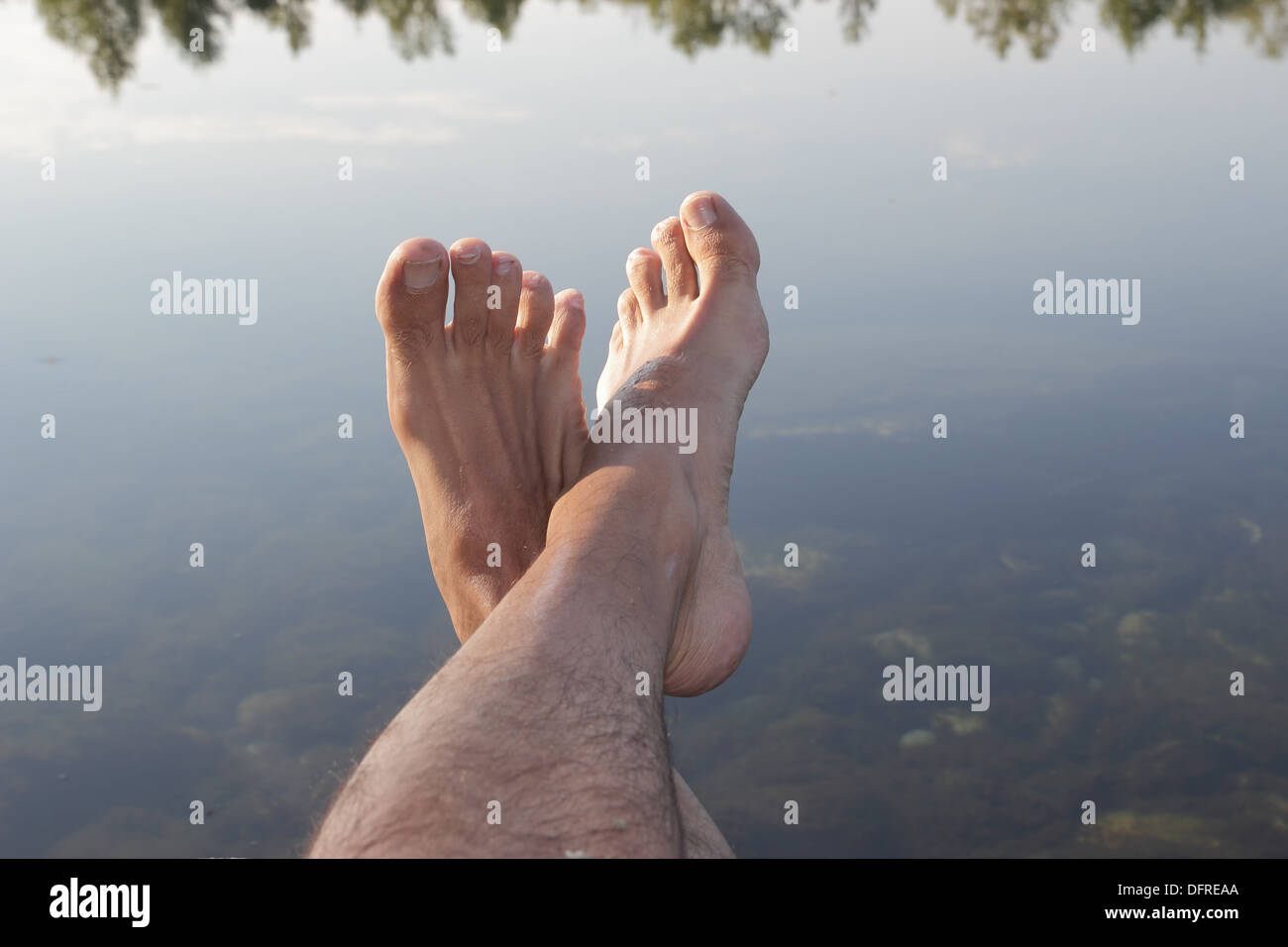 Rilassante piedi maschio su un corpo di acqua Foto Stock