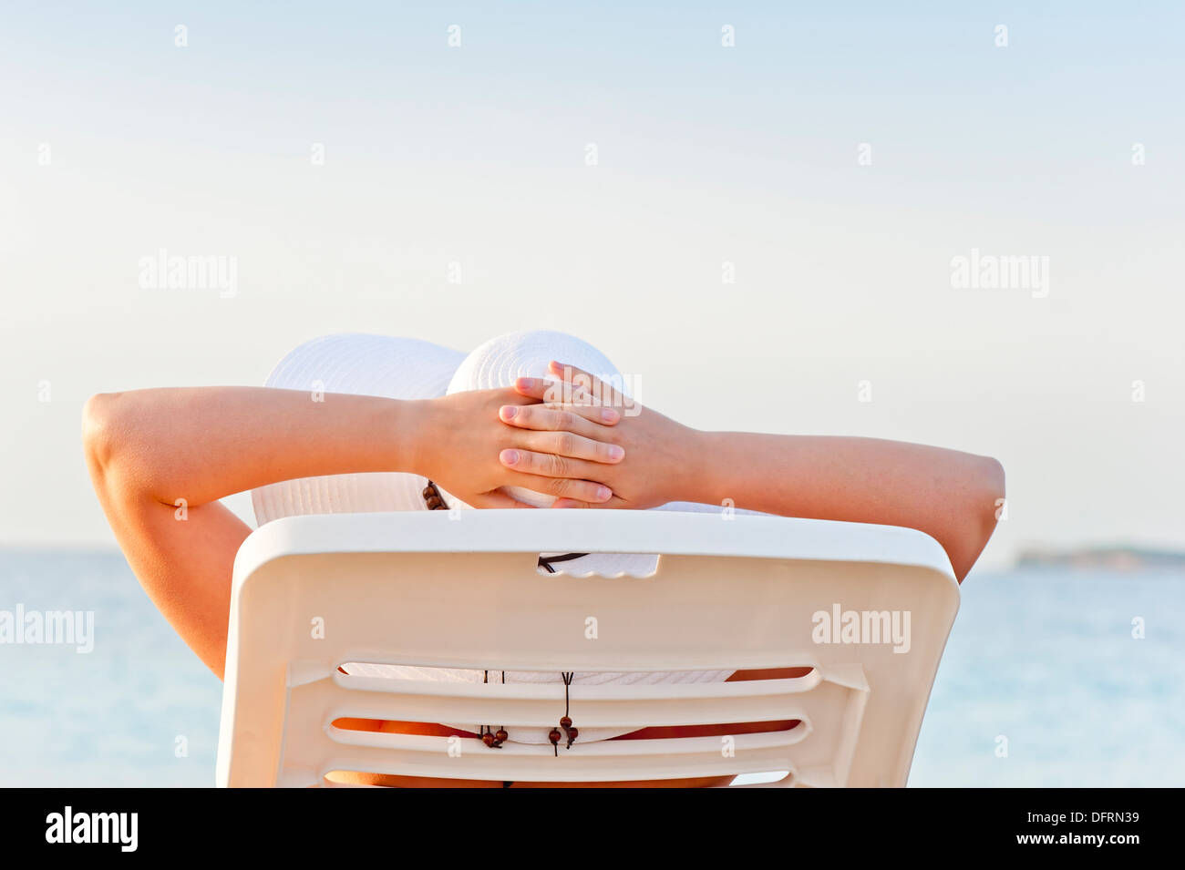 La donna in vacanza in spiaggia in una sedia a sdraio Foto Stock