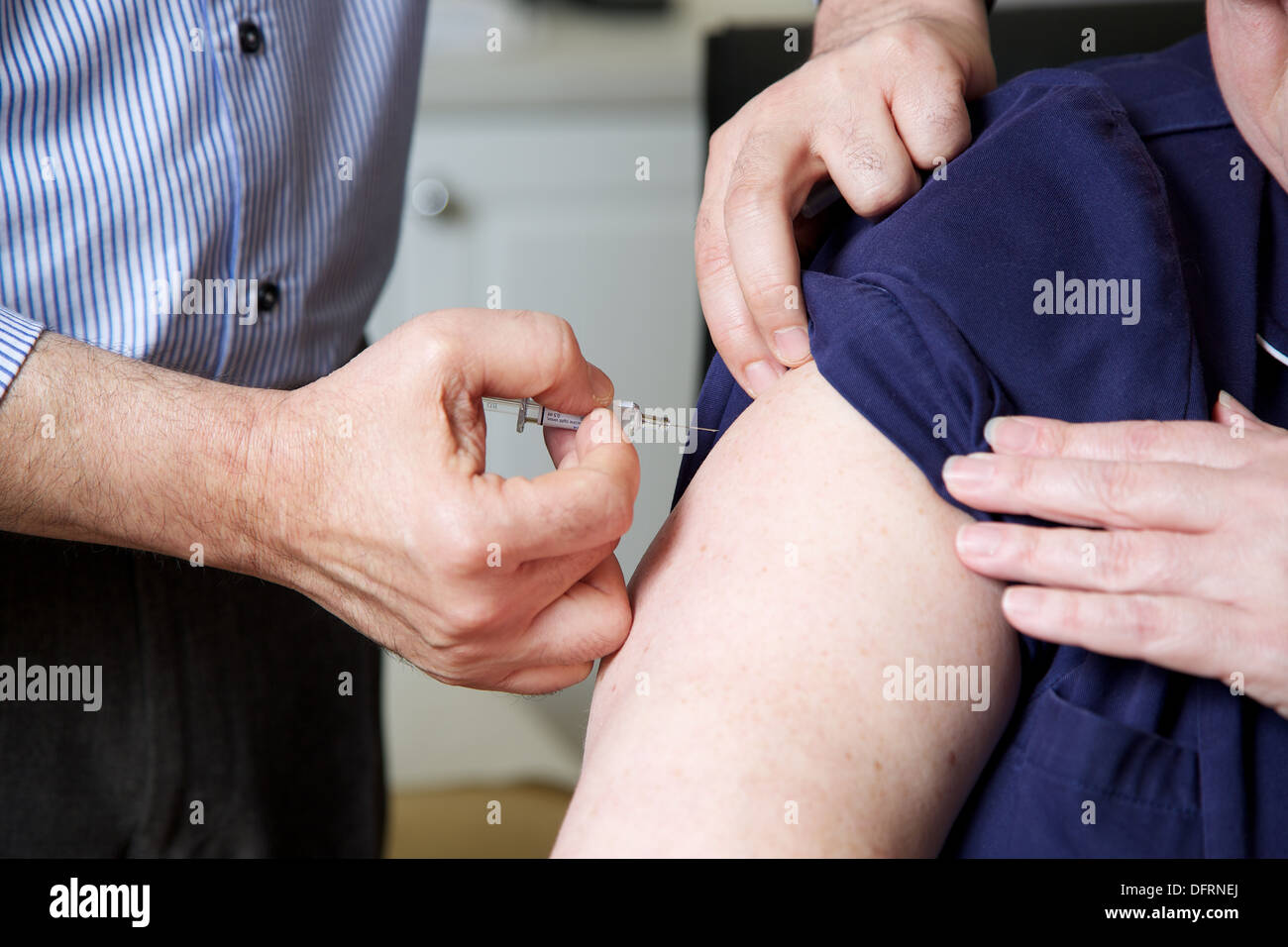 Medico GP prepara per dare il vaccino iniezione per un paziente Foto Stock