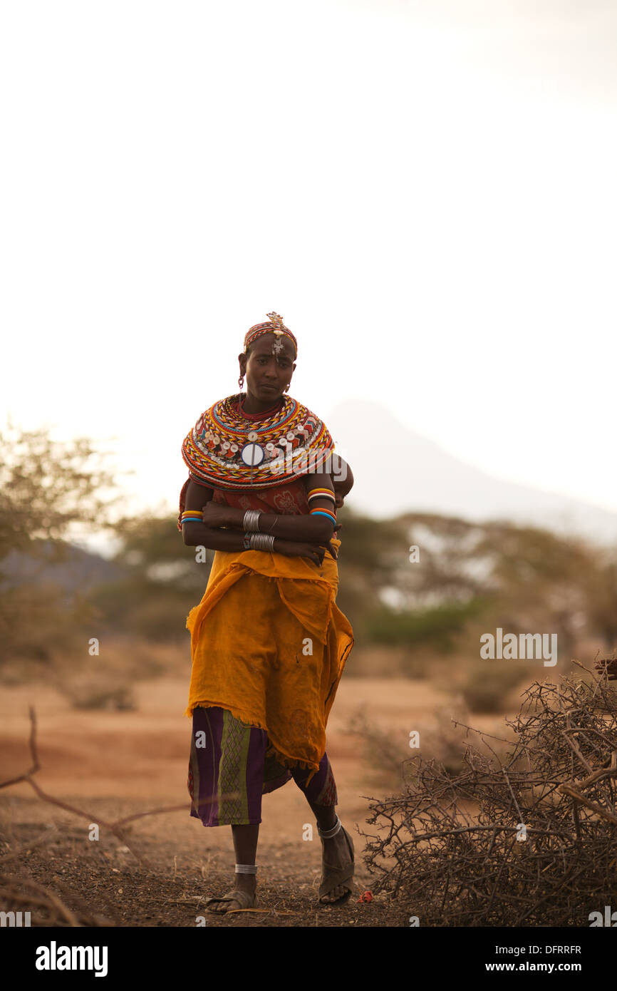 Una donna Rendille tenendo il suo bambino sulla schiena entra nel suo villaggio, vicino a Laisamis, Kenya Foto Stock