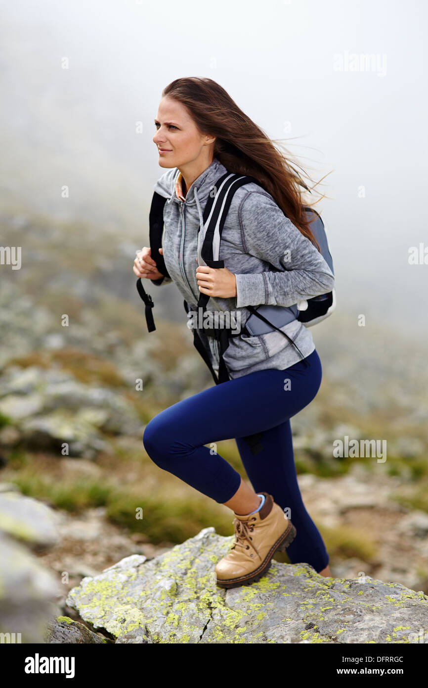 Donna escursionista con zaino arrampicata in montagna su un sfondo nebbioso Foto Stock