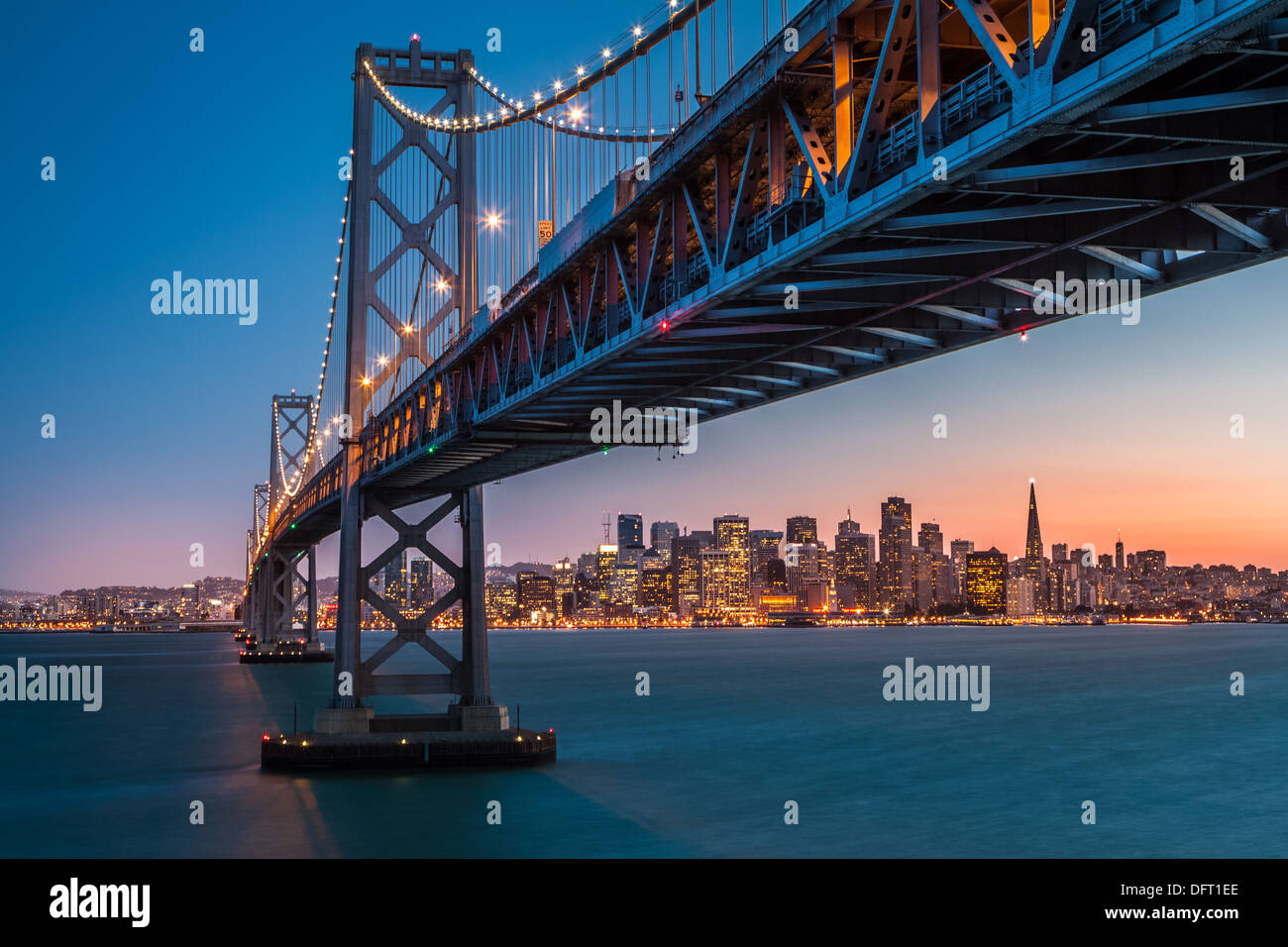 Skyline di San Francisco incorniciato da Bay Bridge al tramonto Foto Stock