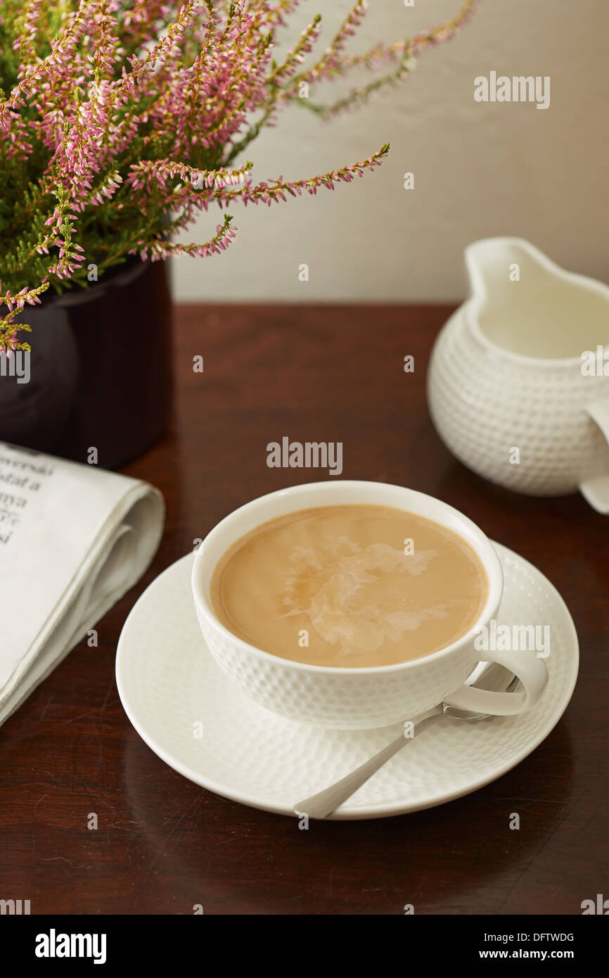 Caffè con latte di domenica mattina la tabella con un giornale e pianta Foto Stock