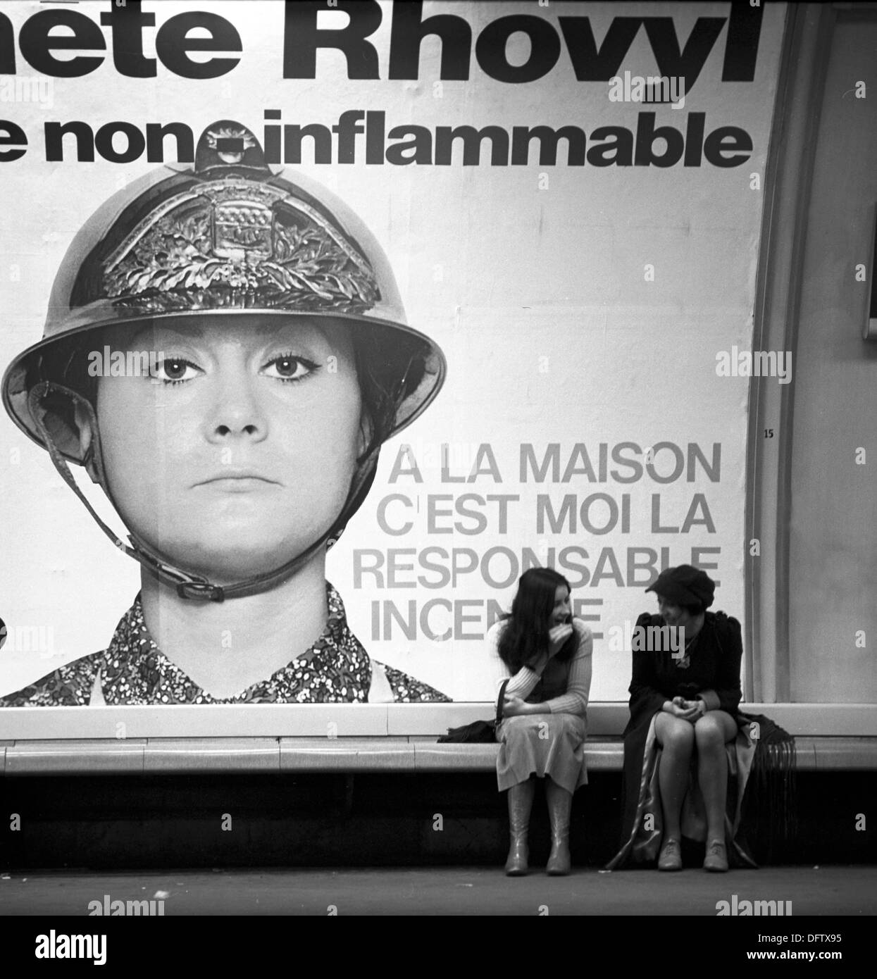Due donne siedono sotto un annuncio pubblicitario per tessuti sintetici e di parlare a Parigi nel novembre 1970. Il messaggio pubblicitario loda l'infiammabilità del materiale. Lo slogan recita: 'a casa, io sono responsabile per la conflagrazione." Foto: Wilfried Glienke Foto Stock