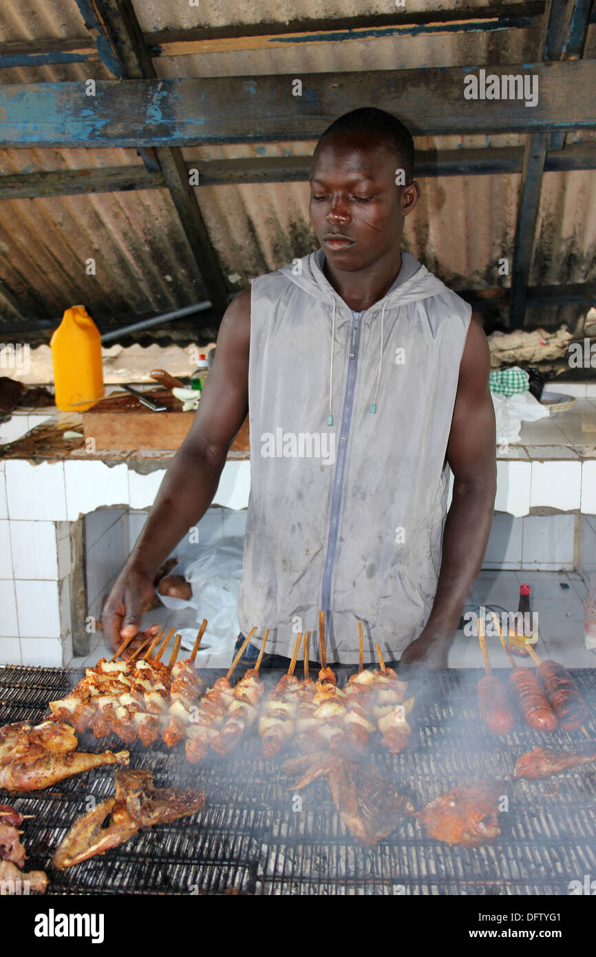 Giovane uomo del Ghana barbecue di carne su spiedini Foto Stock