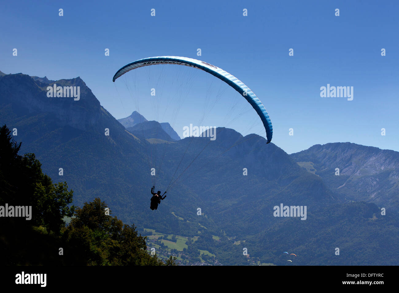 Pilota di parapendio e il passeggero oltre le Alpi in estate nella regione di Annecy, Haute Savoie, Francia Foto Stock