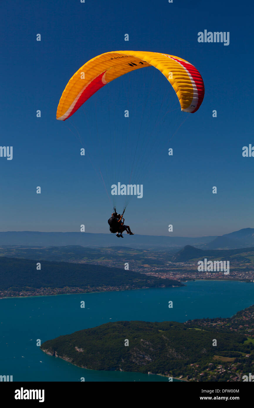 Giallo hanglider contro un cielo azzurro volare sopra il lago di Annecy, Haute Savoie, Francia Foto Stock