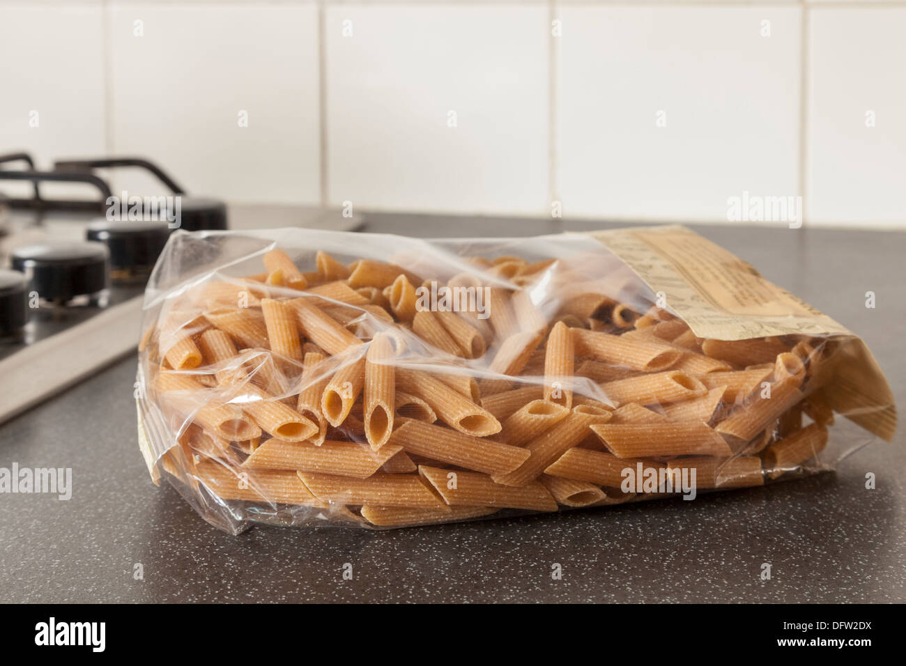 Bustina di plastica di secche frumento integrale penne pasta su una cucina superficie di lavoro Foto Stock