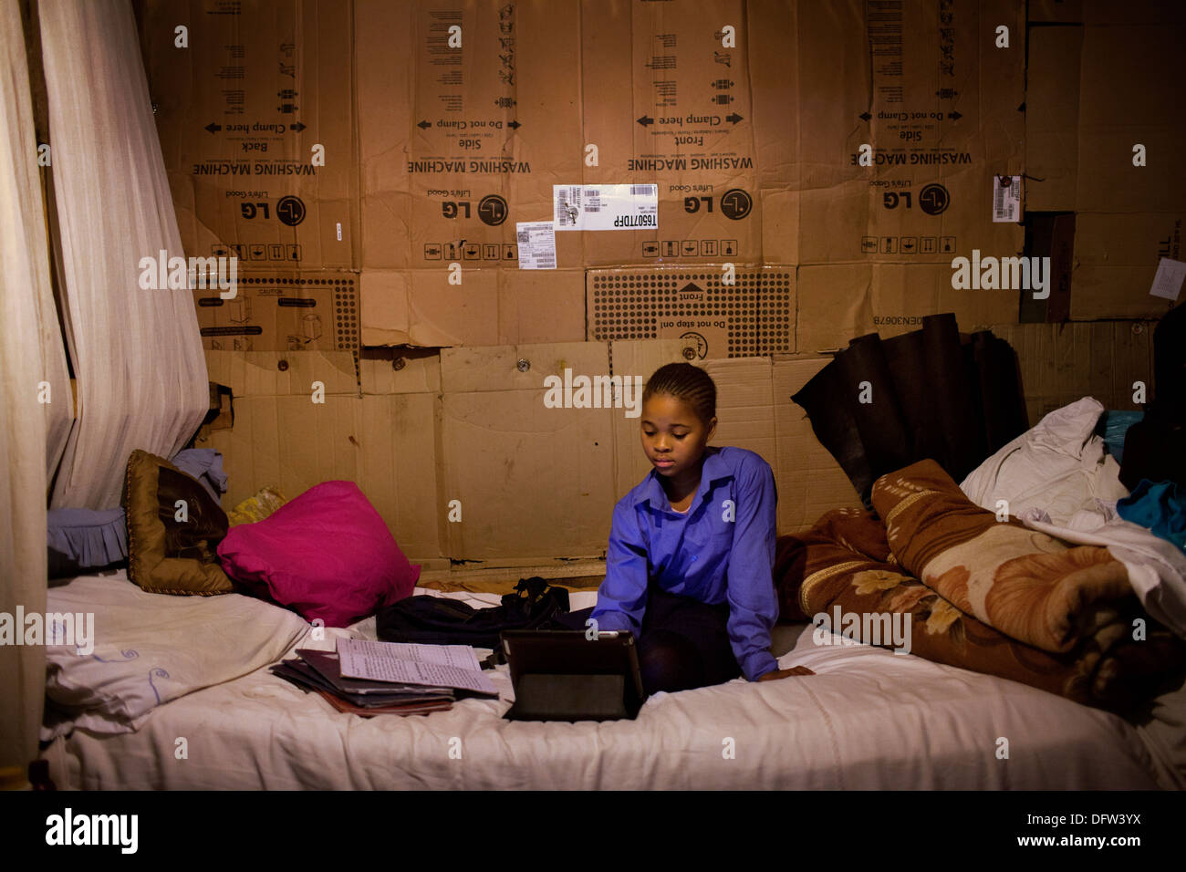 Phelela, 13 anni, svolgendo compiti su un iPad nella sua camera da letto in Nyanga, Cape Town, Sud Africa Foto Stock