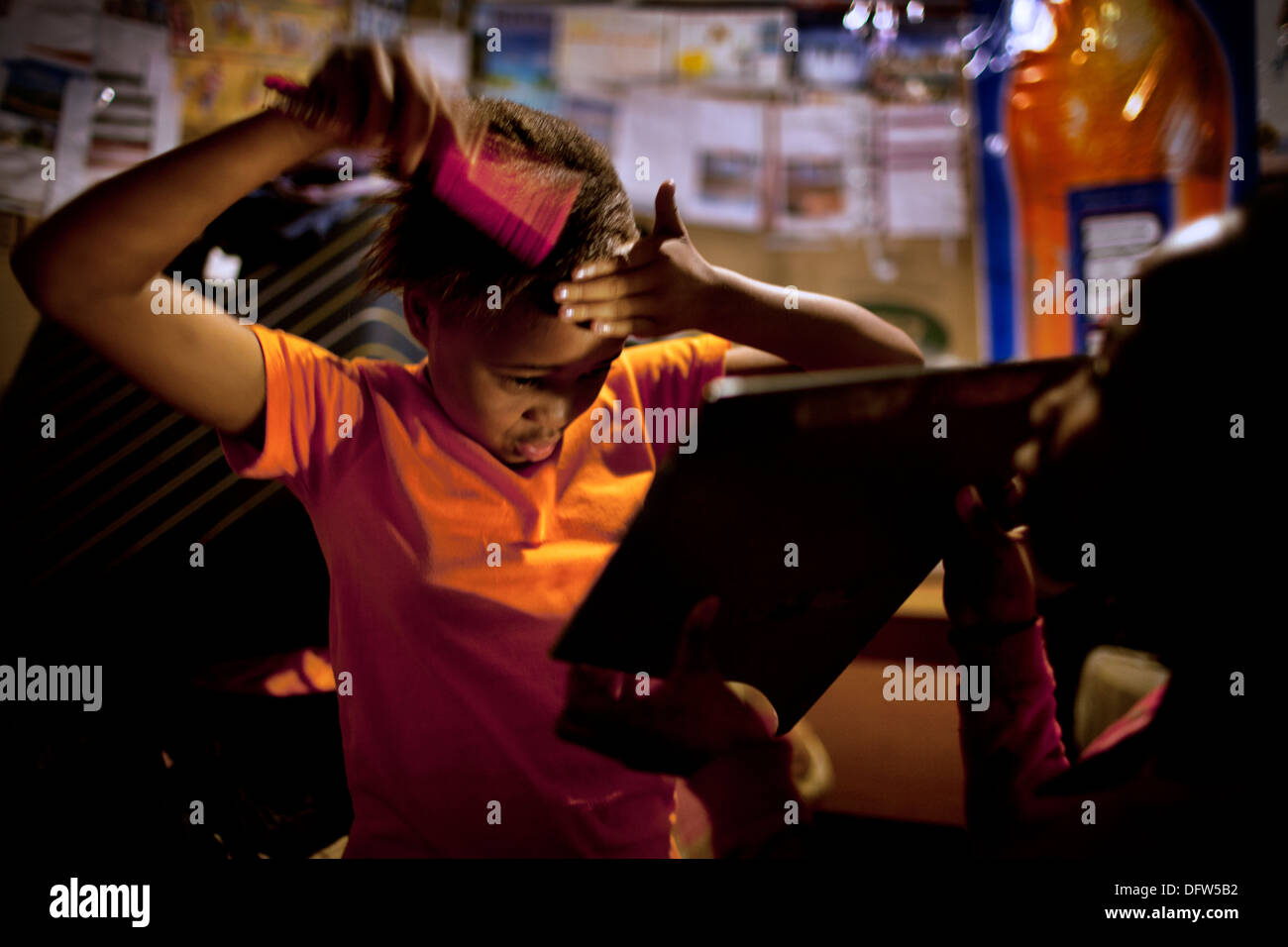 Phelela, 13 anni, spazzolare i capelli nella sua camera da letto a casa in Nyanga, Cape Town, Sud Africa Foto Stock