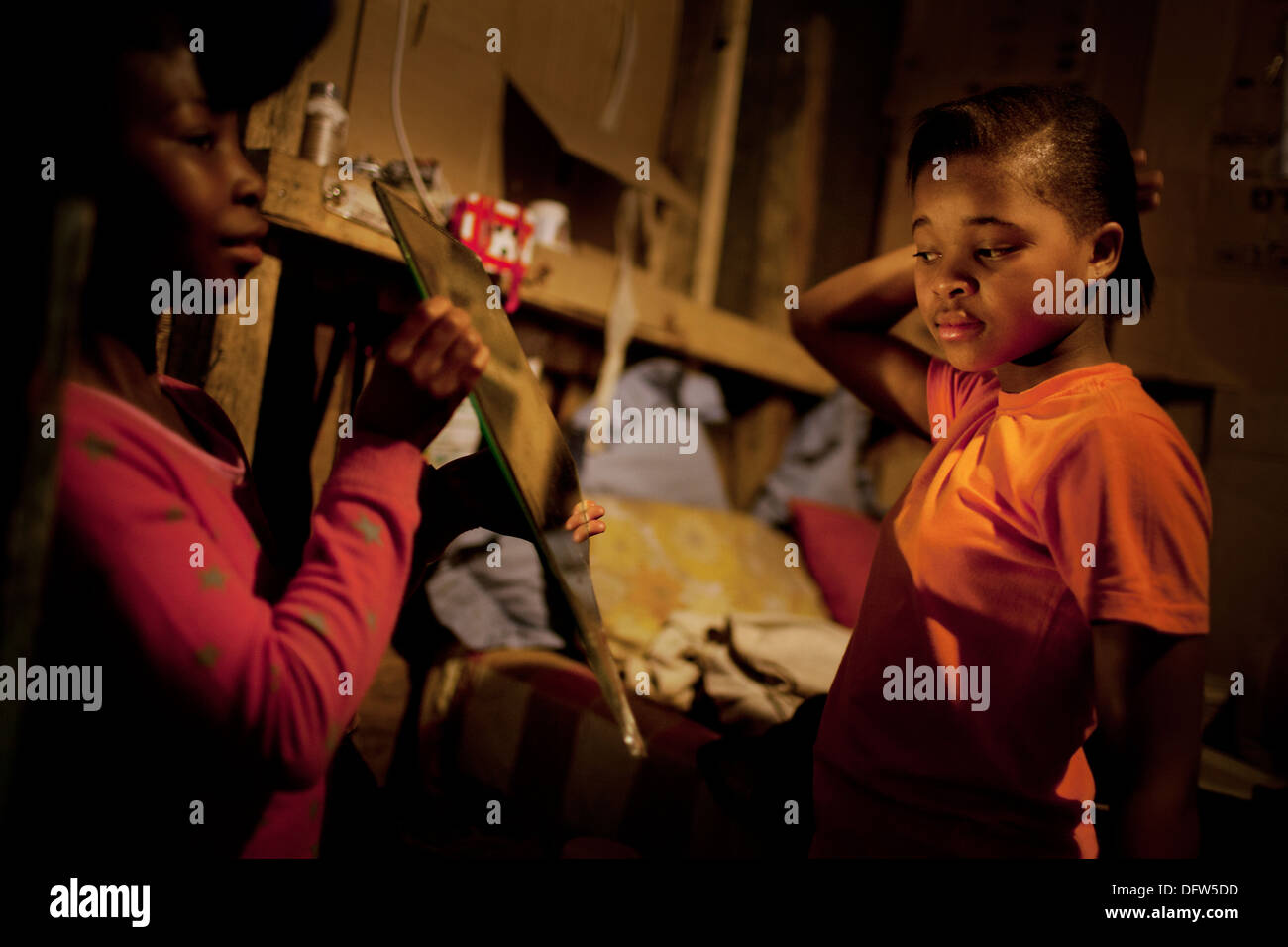 Phelela, 13 anni, spazzolare i capelli nella sua camera da letto a casa in Nyanga, Cape Town, Sud Africa Foto Stock