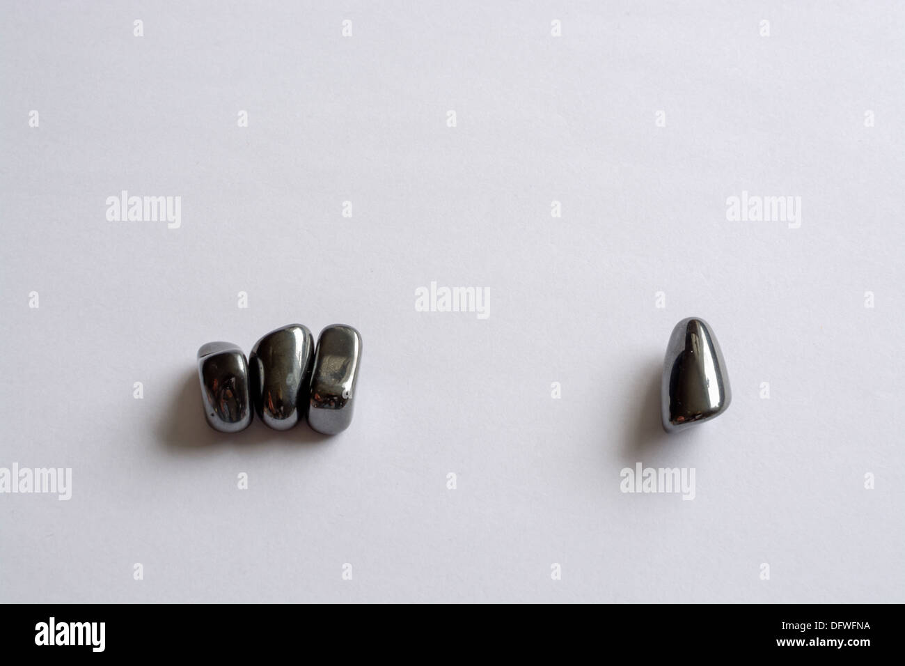Pietre di magnetite, tre seduti insieme e uno è separata - la legge di attrazione. Foto Stock
