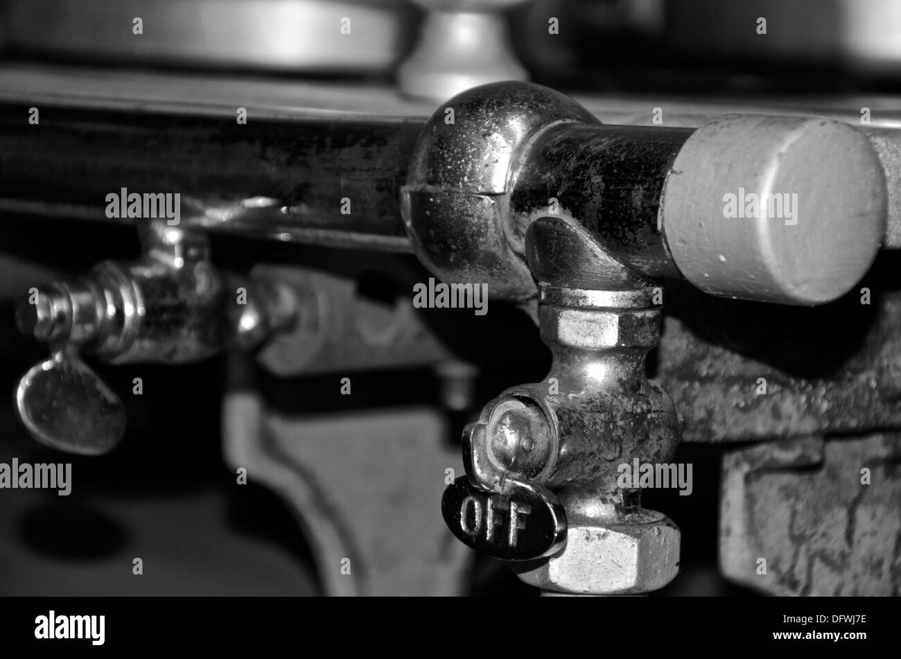 Il 'OFF' interruttore di una 1940's industriale fornello a gas in monocromatico. Foto Stock