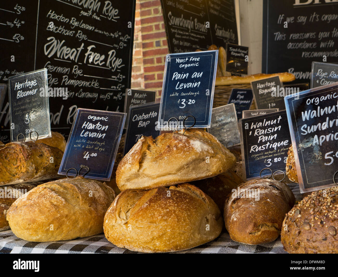 Varietà di attraente fatto a mano pane artigianale sul display per la vendita su piccola panetteria di stallo elevata di Guildford Street Surrey UK Foto Stock