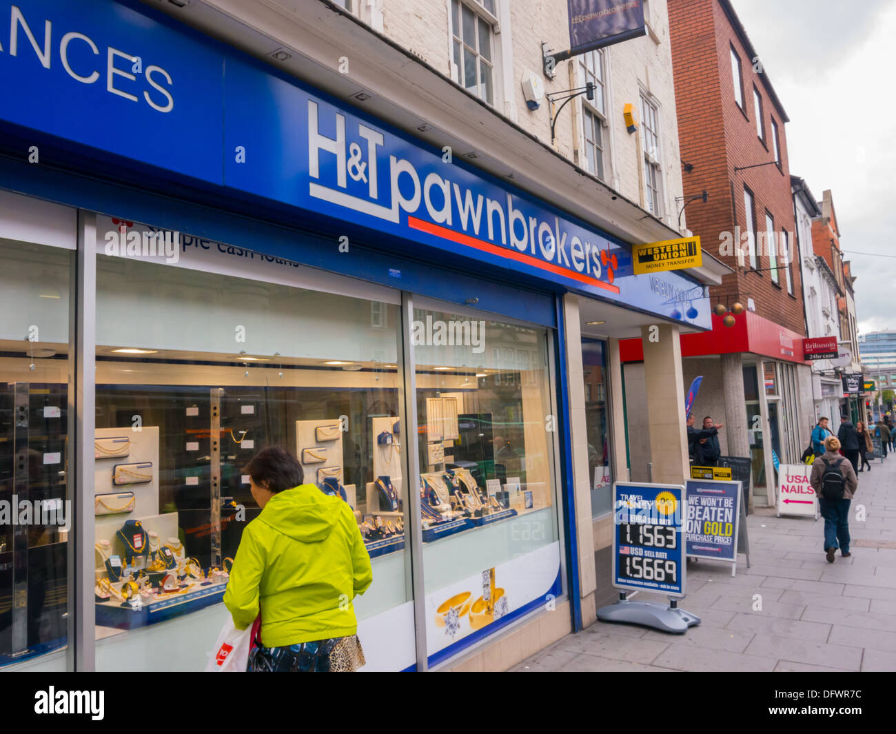 Donna che guarda nella finestra di H&T Pawnbrokers in Nottingham a impegnato gioielli. Foto Stock