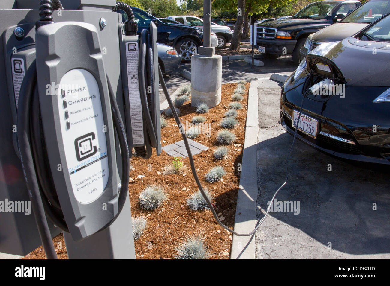 EV stazioni di ricarica con il plug-in auto elettrico collegato alla presa di corrente per ricaricare le sue batterie in presso una società di parcheggio Foto Stock