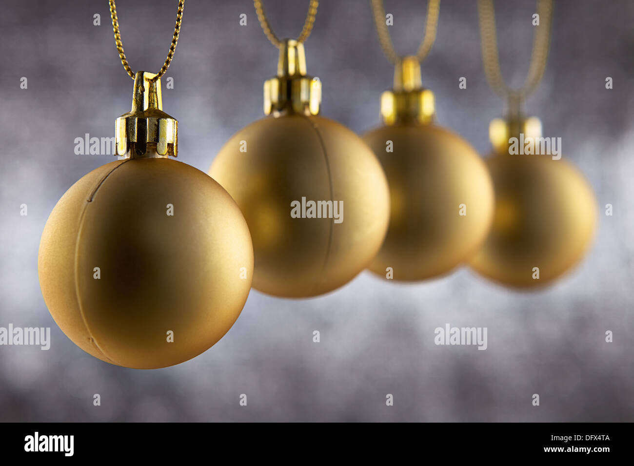 Quattro decorazione di Natale sfera appeso contro un silver glitter sfondo con profondità di campo Foto Stock