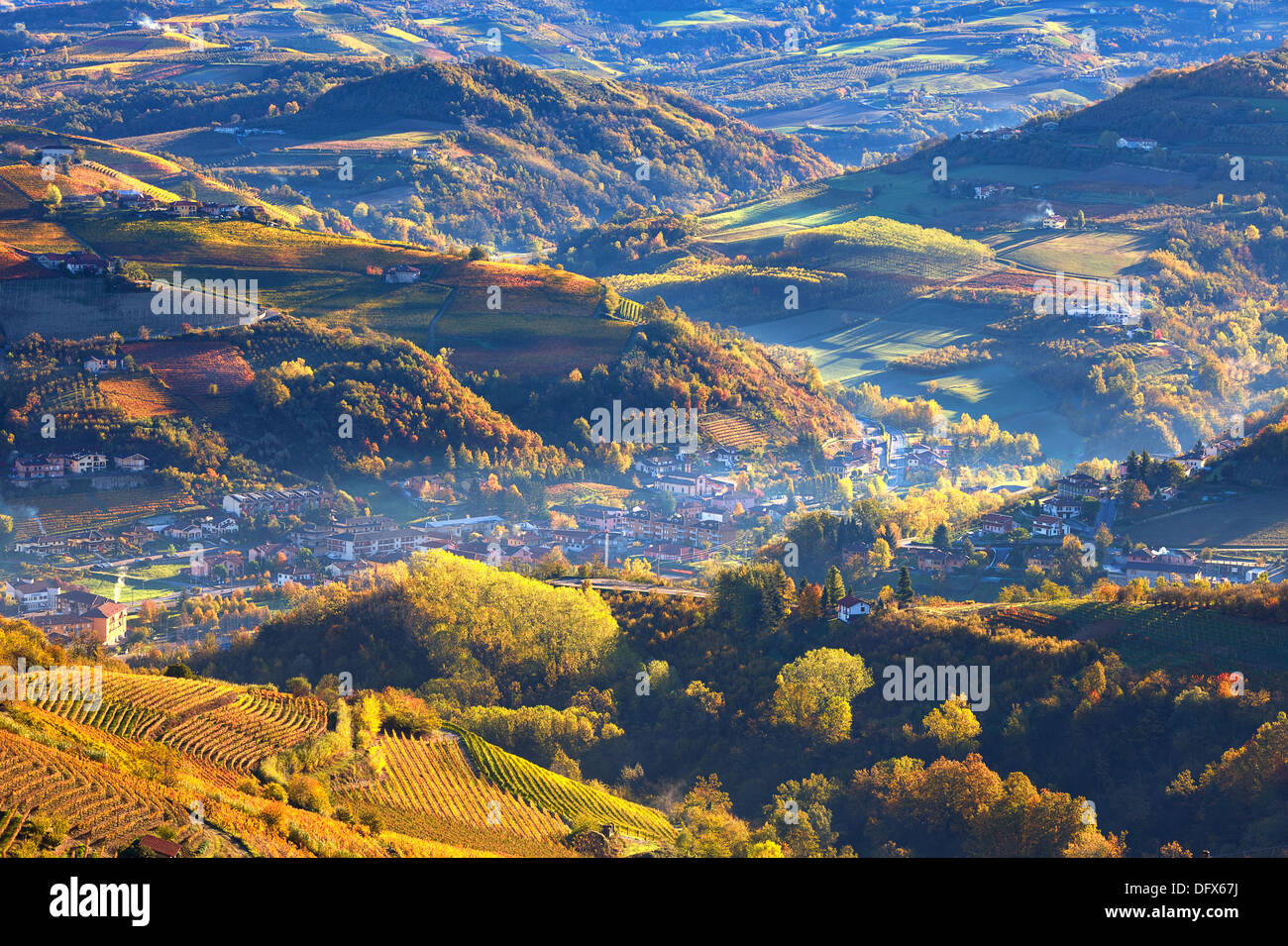 Mattinata nebbiosa su piccole città tra autunnale di colline e vigneti del Piemonte, Italia settentrionale (vista da sopra). Foto Stock