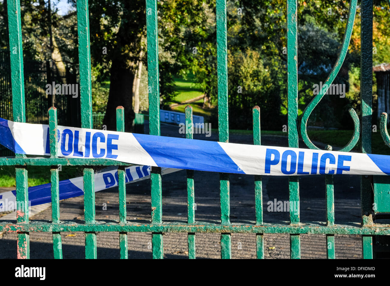 Nastro di polizia tesa attraverso il cancello di ingresso a un parco pubblico a seguito di un omicidio Foto Stock