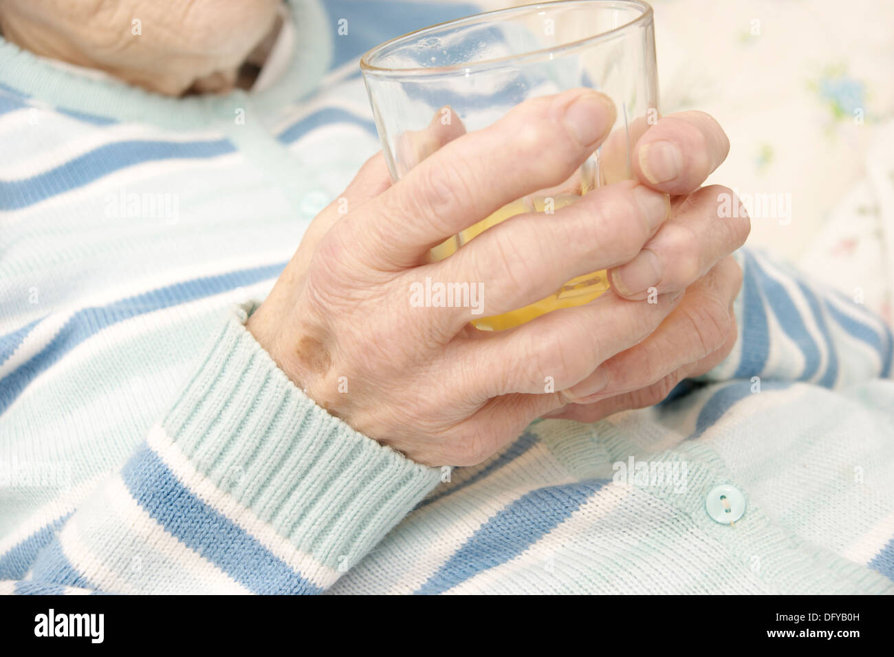 Donna anziana paziente con in mano un bicchiere con un bicchiere di succo di arancia Foto Stock